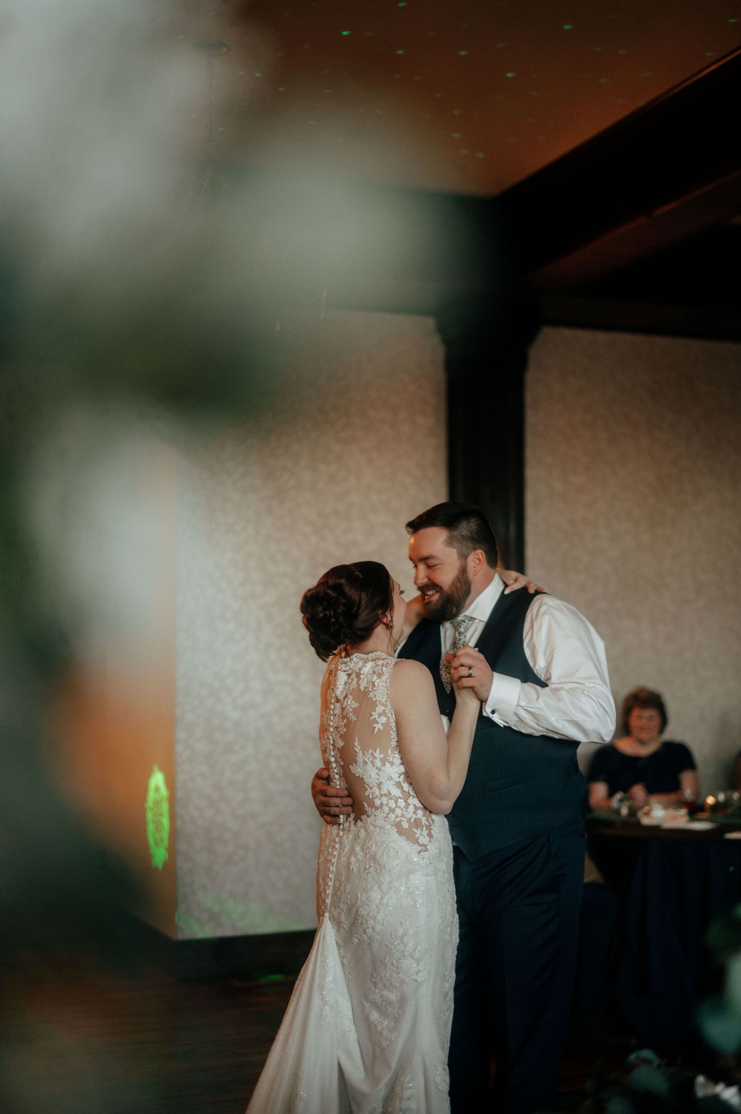 Couple shares an intimate dance moment in a warmly lit reception venue.