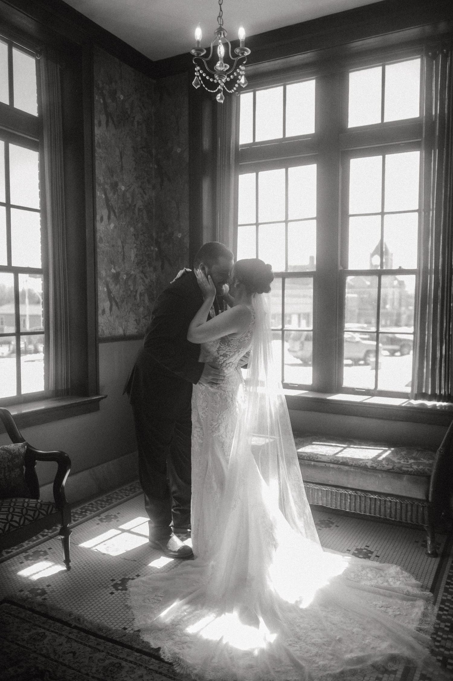 Black and white bridal portraits with dramatic window lighting in a vintage setting.