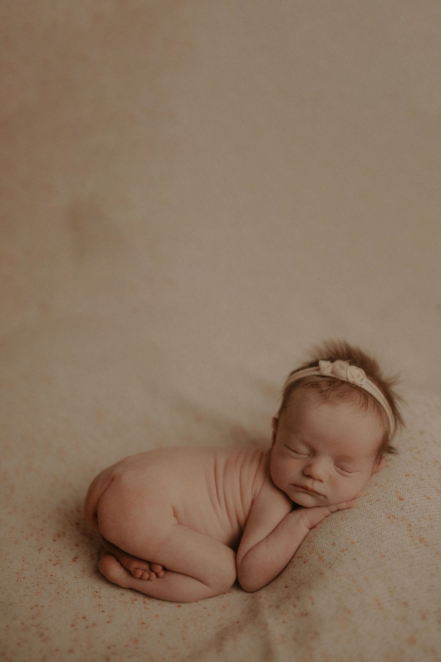 Peaceful sleeping newborn posed on soft textured surface.