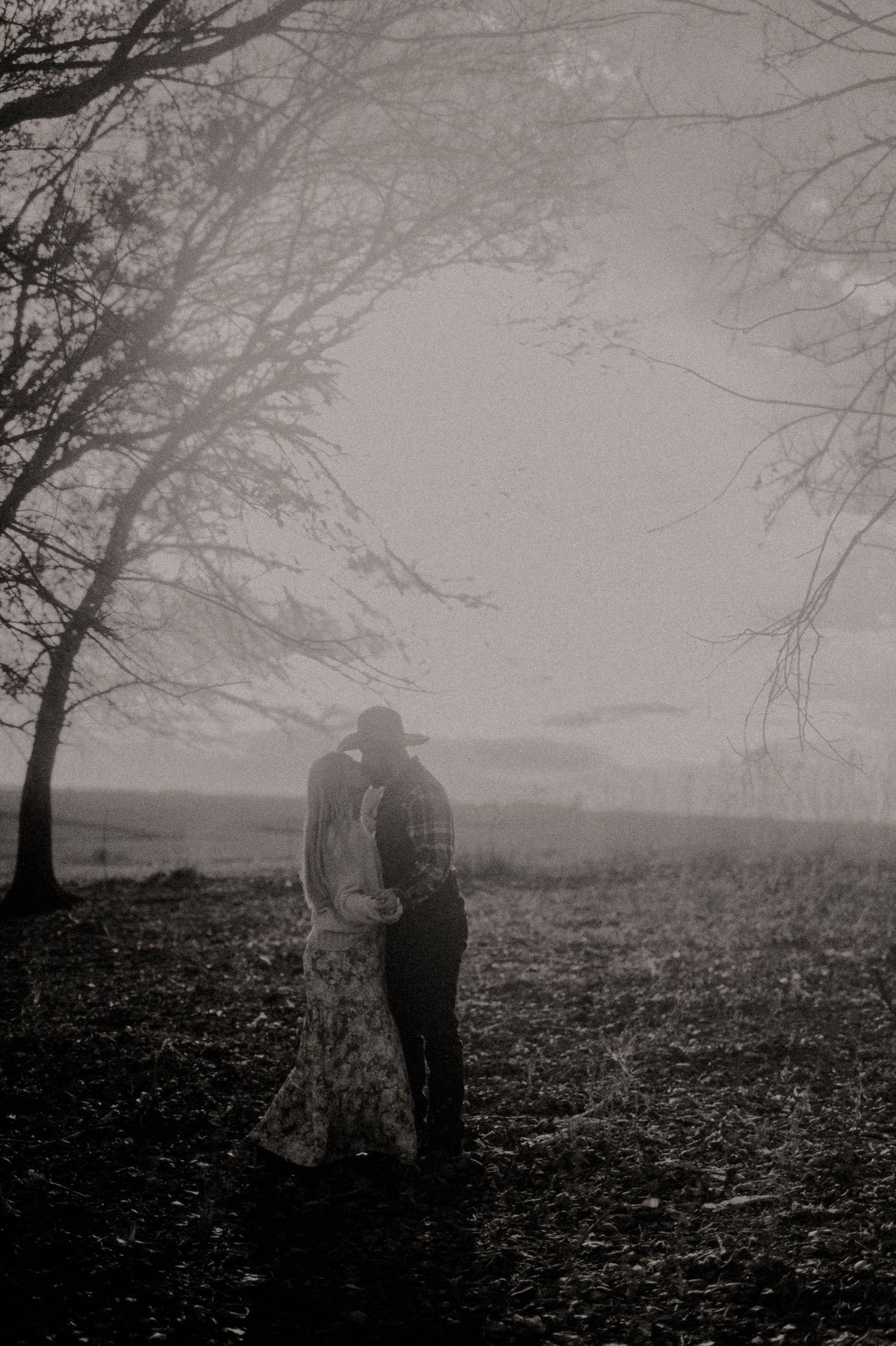 Silhouettes of two people standing in a foggy autumn landscape.