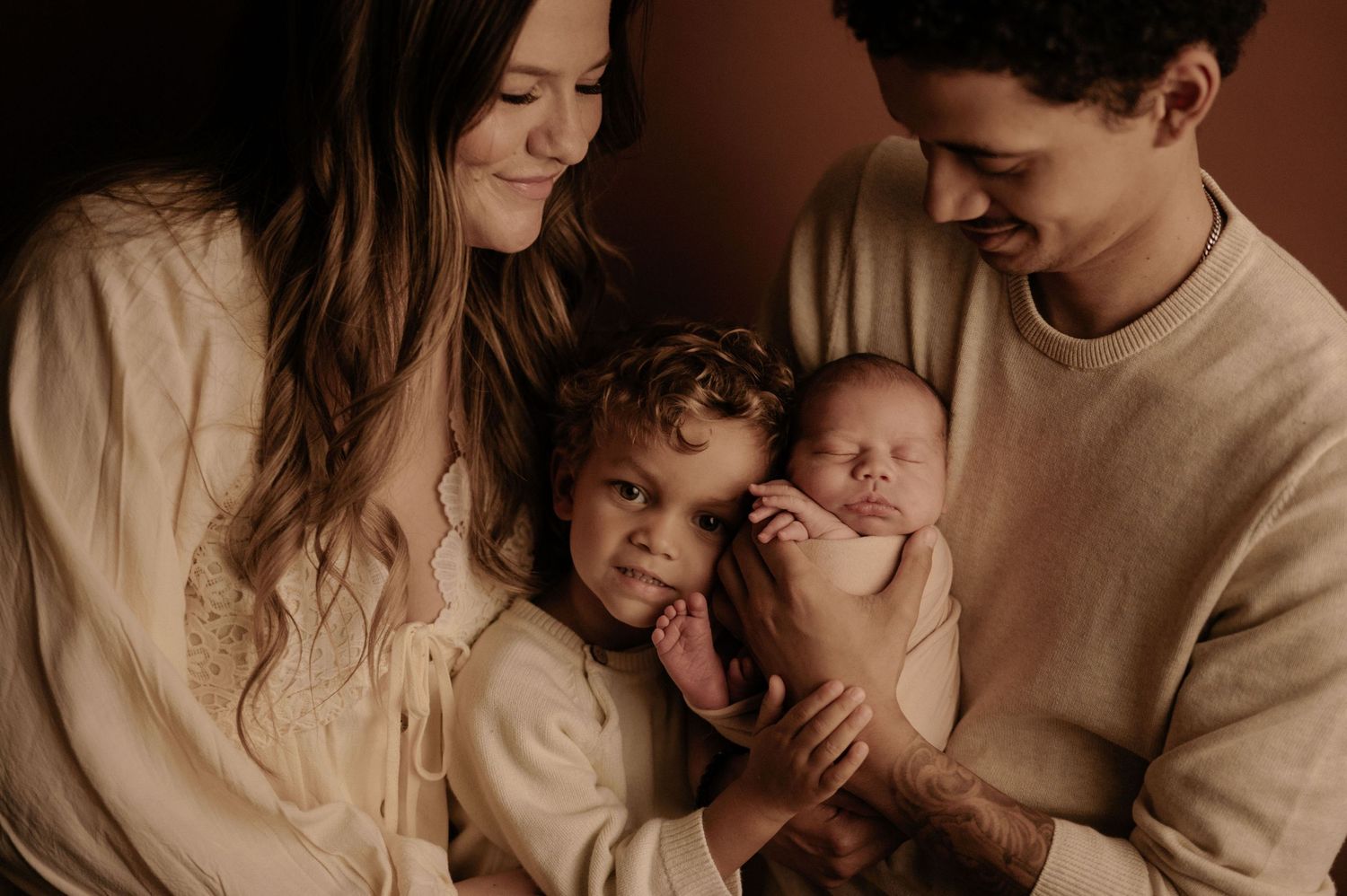 A tender family moment captured in warm neutral tones as they embrace and share affectionate interactions together.