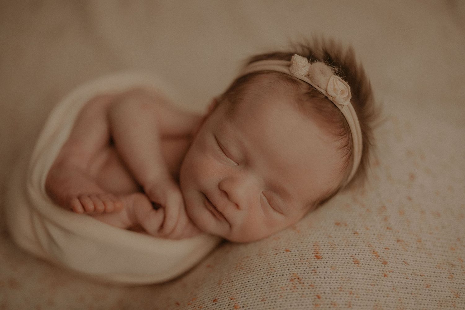 Peaceful sleeping newborn wrapped in soft blankets in neutral tones.