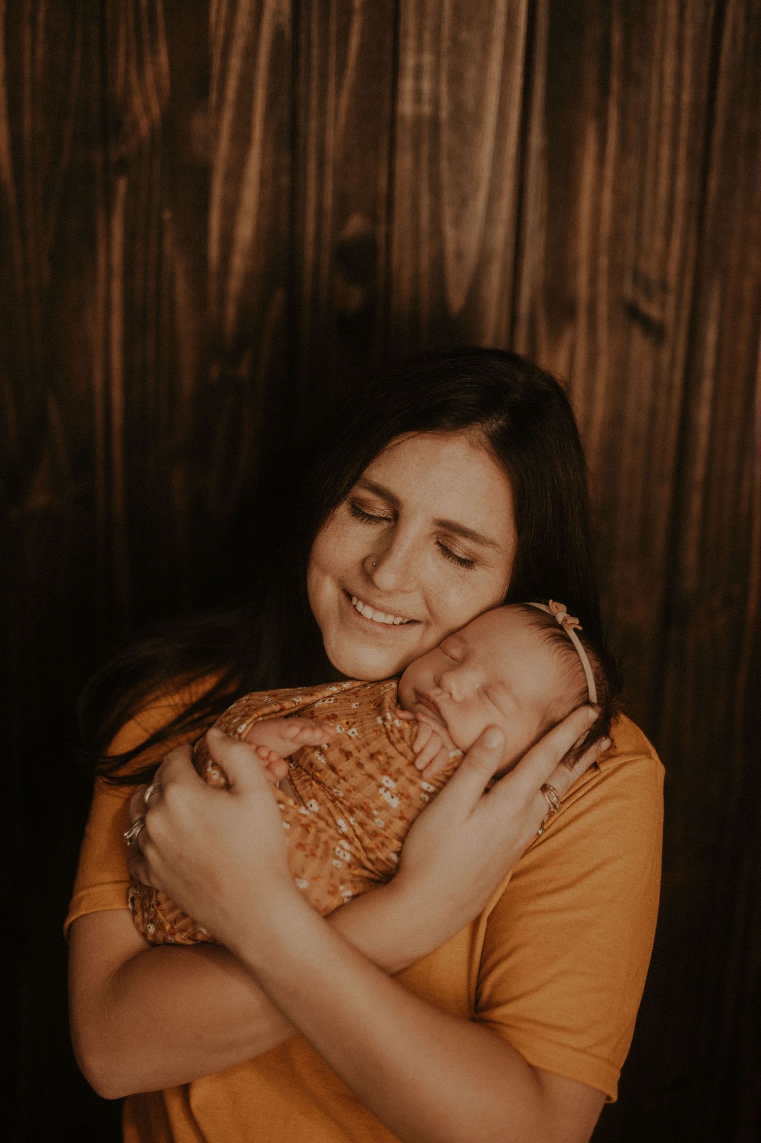 A tender embrace between two people wearing orange and floral clothing in warm lighting against a wooden backdrop.