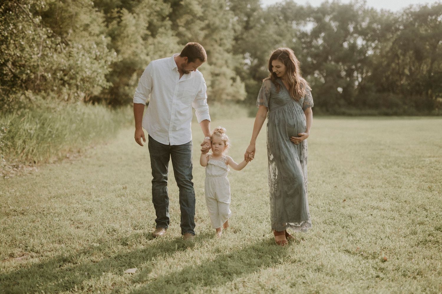 Family enjoying a tender moment together in a sunlit meadow during golden hour.