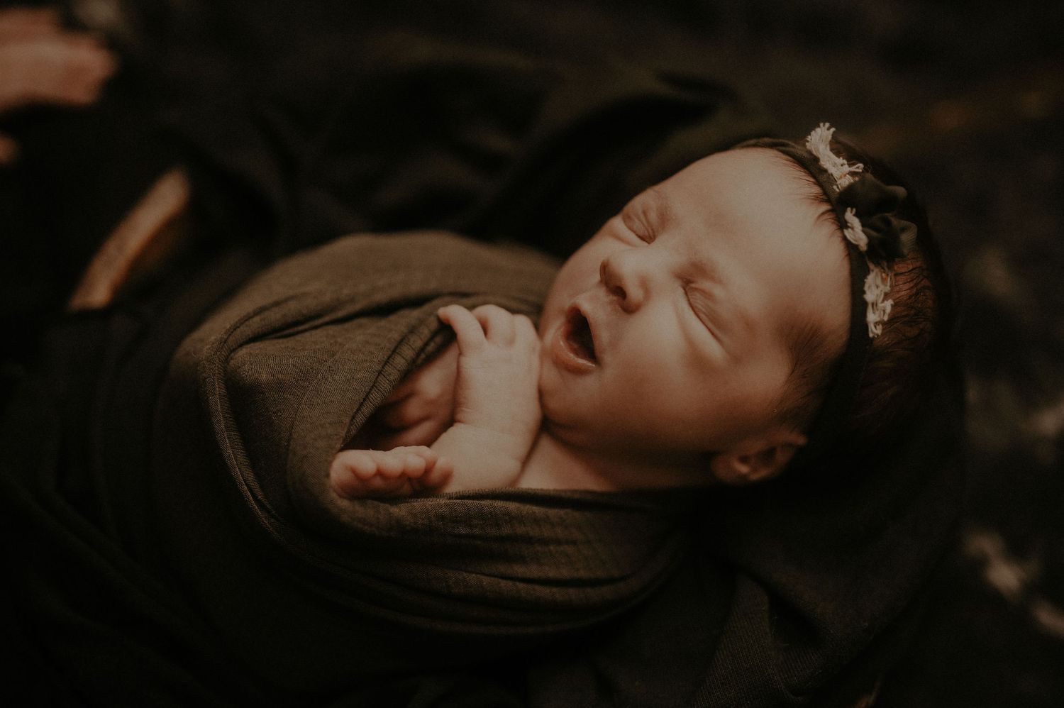 Series of monochrome images showing tender moments between a sleeping newborn and caring hands.