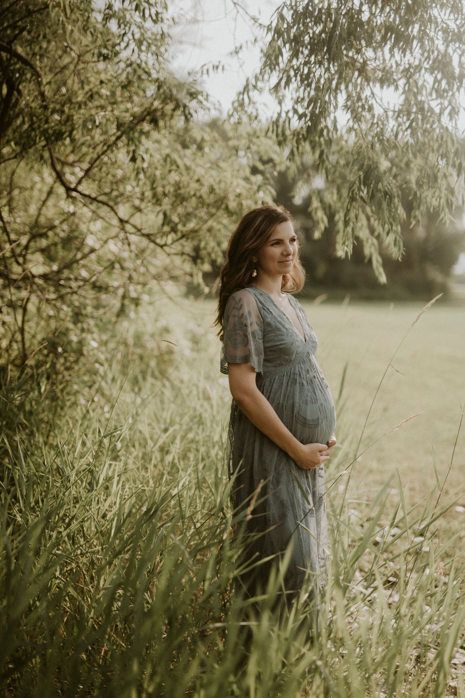A series of dreamy outdoor maternity photos captured in soft natural light among tall grass and willow trees.