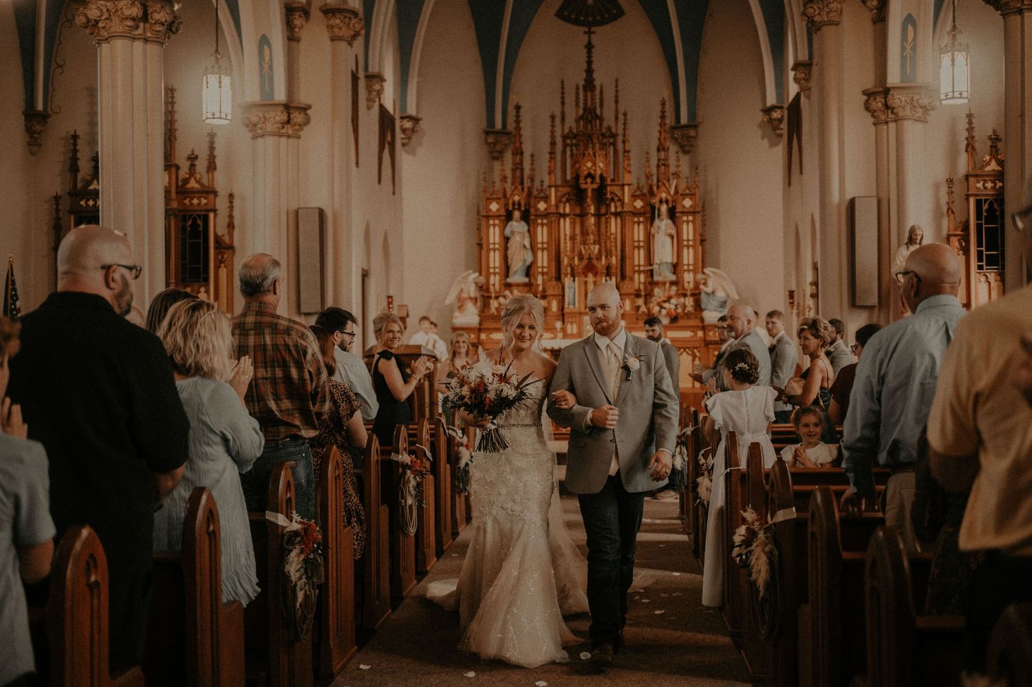 Wedding ceremony in progress inside a beautiful cathedral with vaulted ceilings and wooden pews.