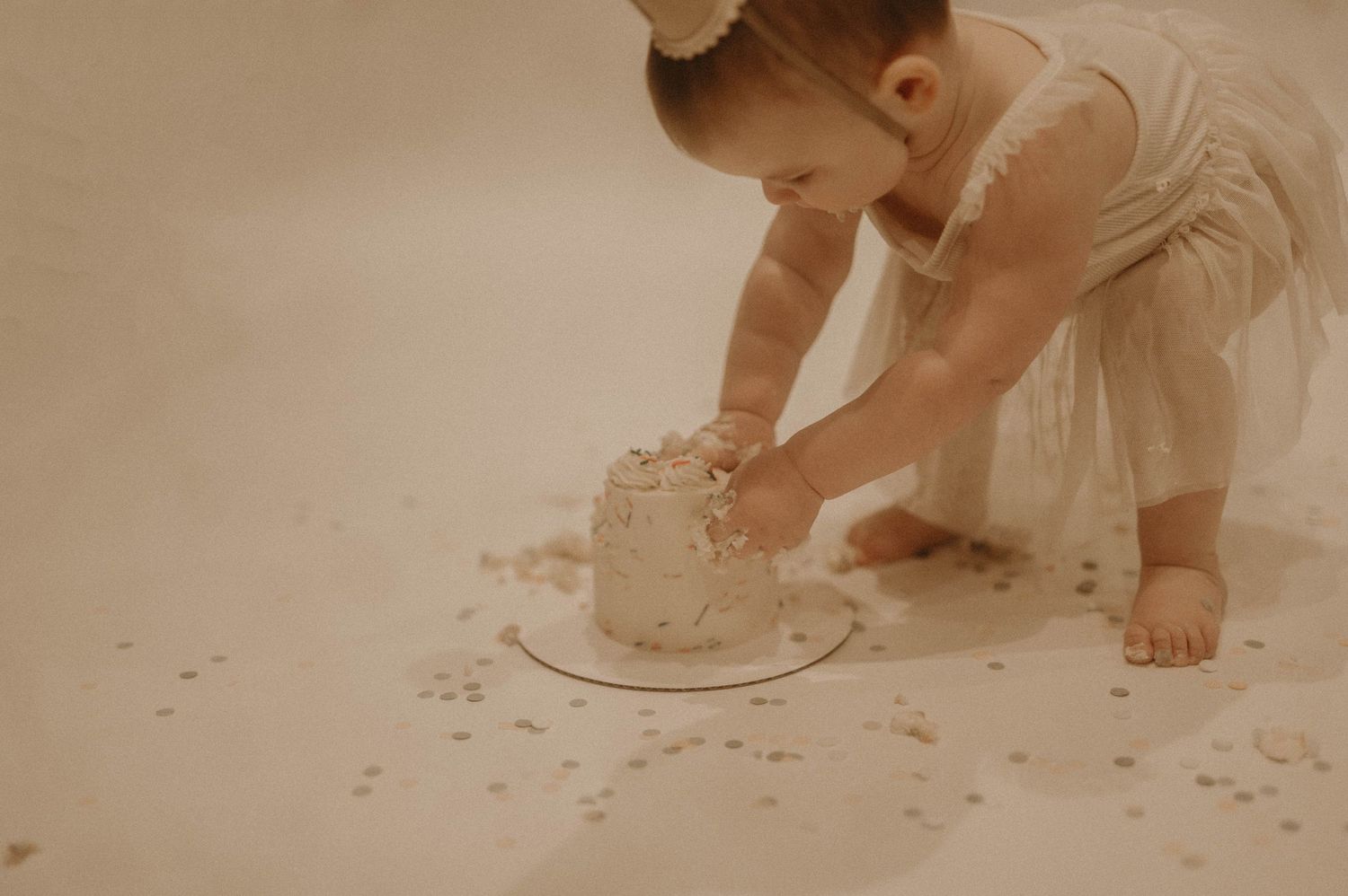 A baby's feet leave tiny footprints in white flour on a wooden floor, creating a trail of playful steps.