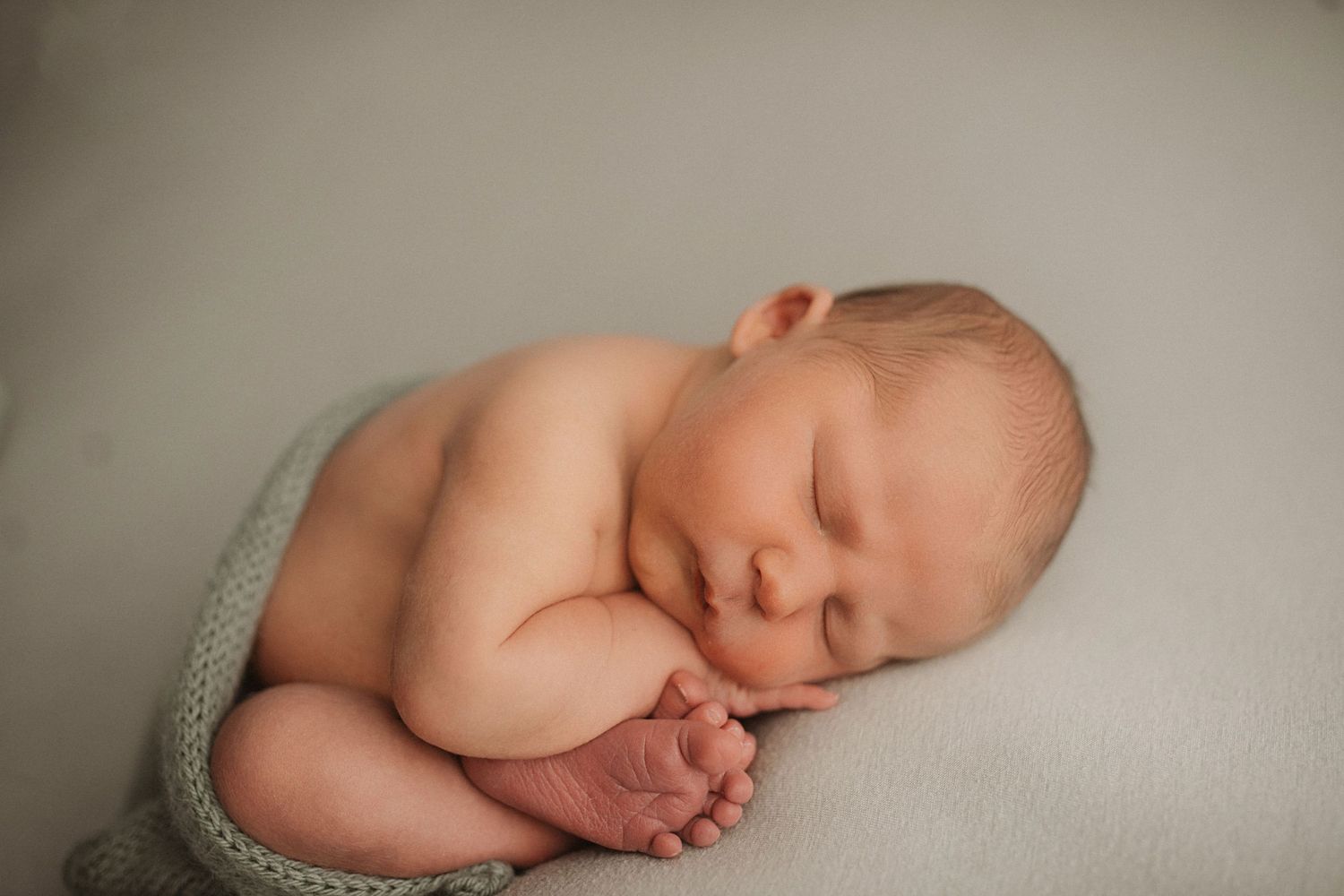 Artistic black and white newborn photography with gentle shadows and soft textures.