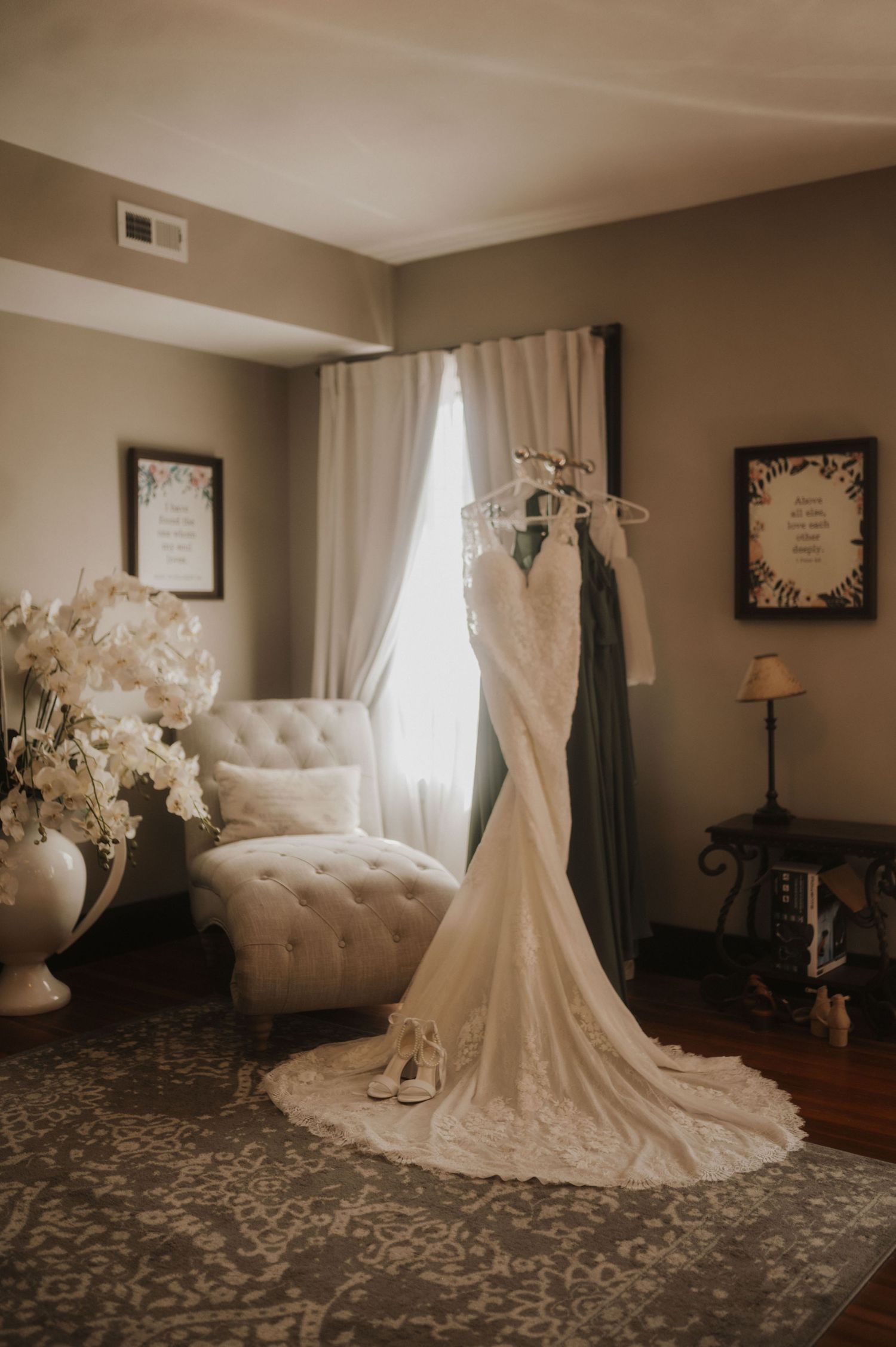 White wedding gown with long train displayed in a room with tufted furniture.