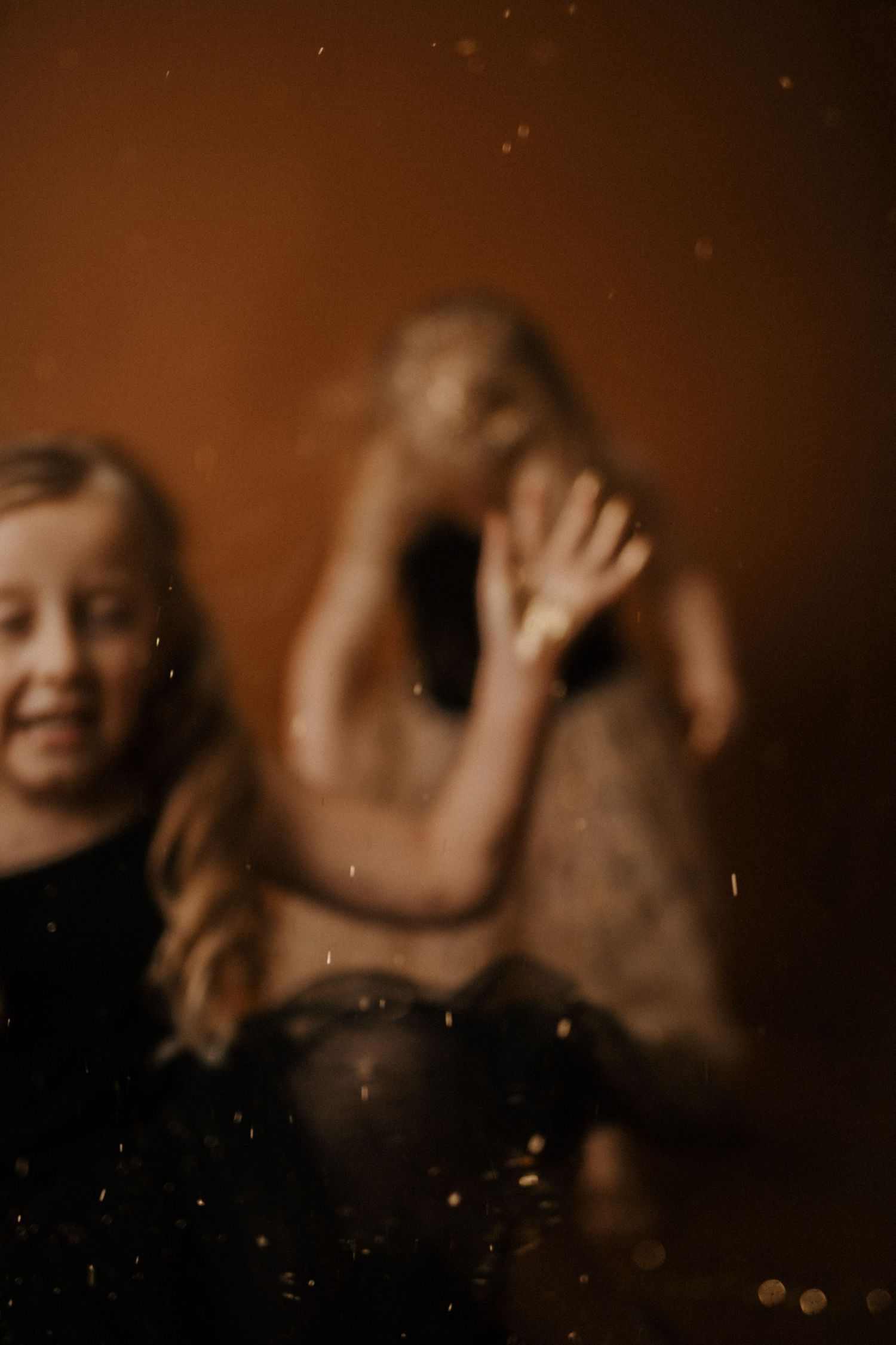 Blurry sepia-toned photo showing joyful candid moment with motion and laughter against dark background.