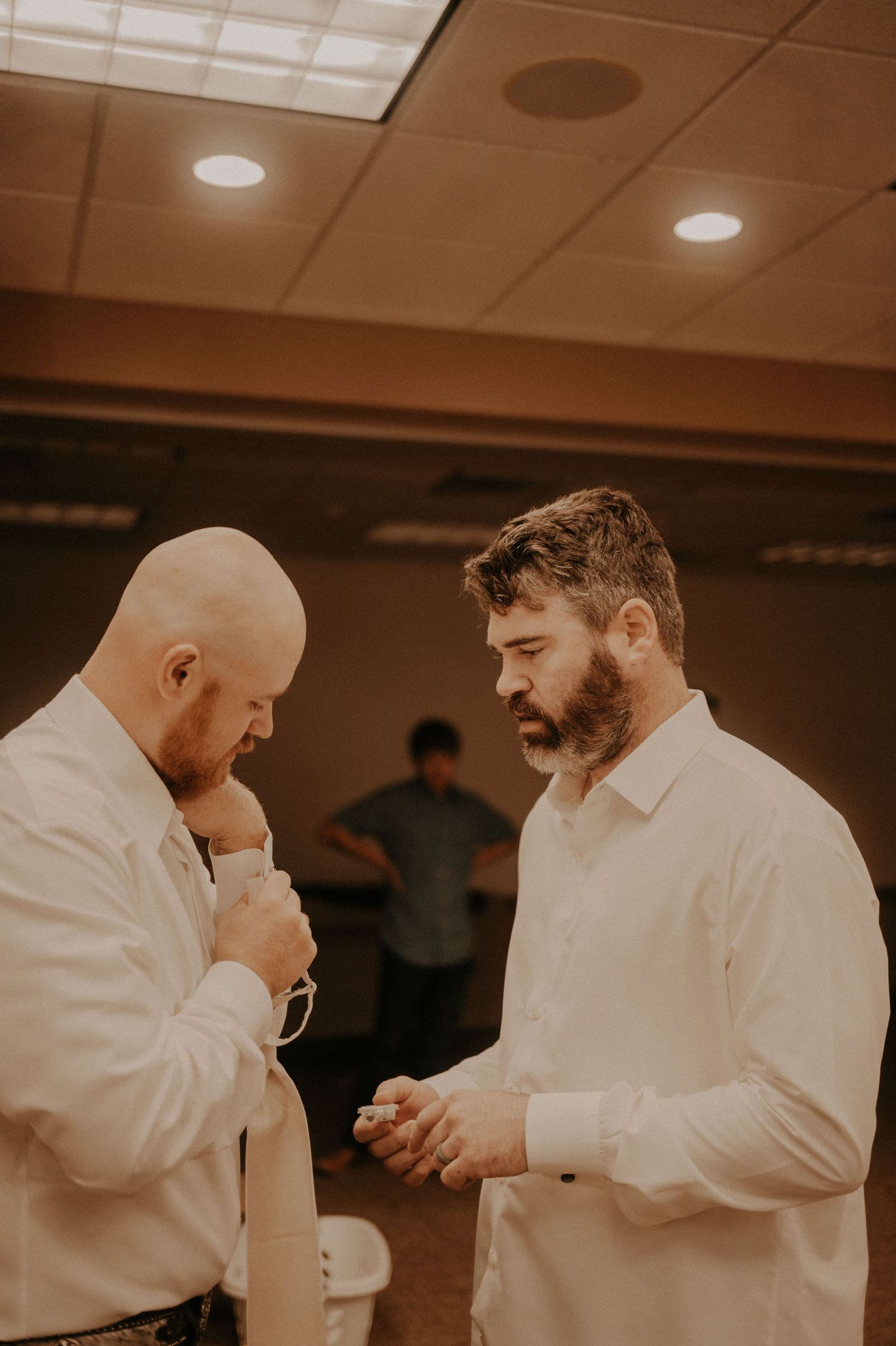 Two figures in white shirts sharing an intimate moment in a warm-toned indoor setting.