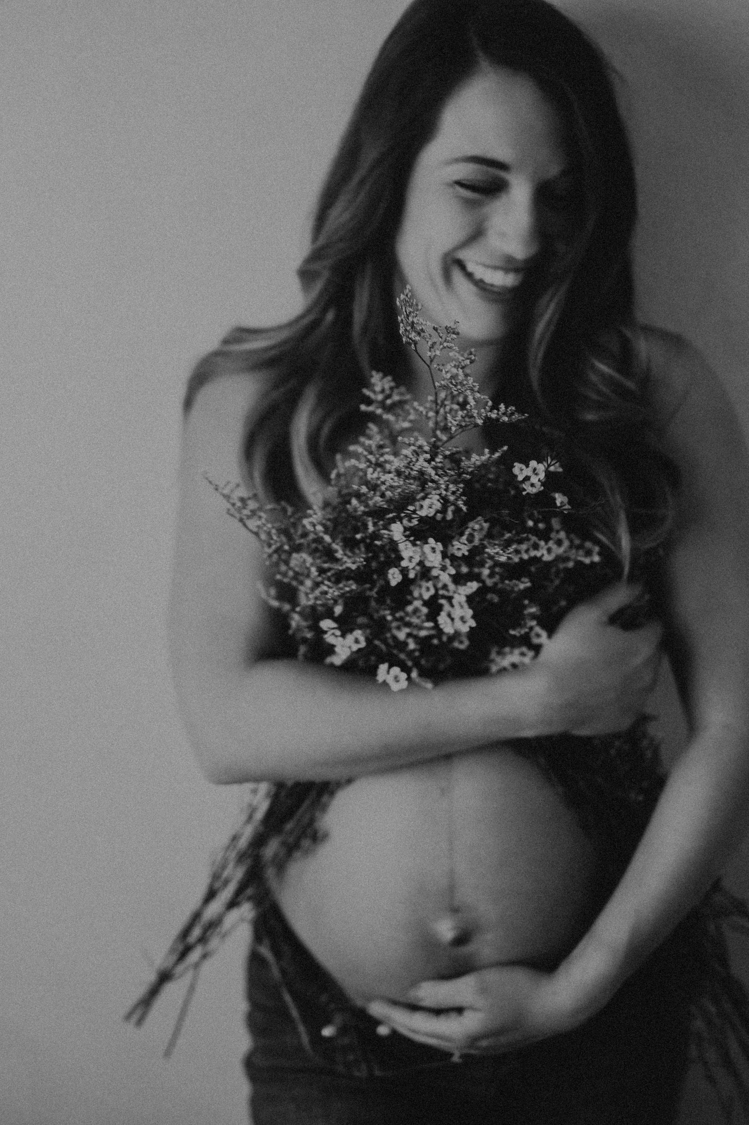 Black and white artistic maternity portrait with dried flowers.