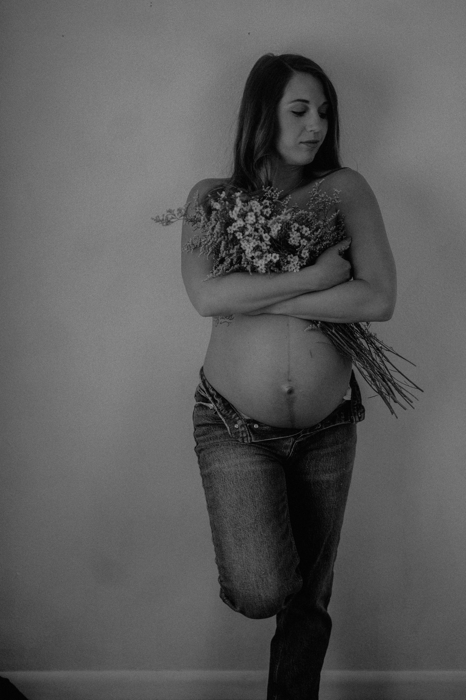 Black and white maternity portrait with delicate dried flowers.