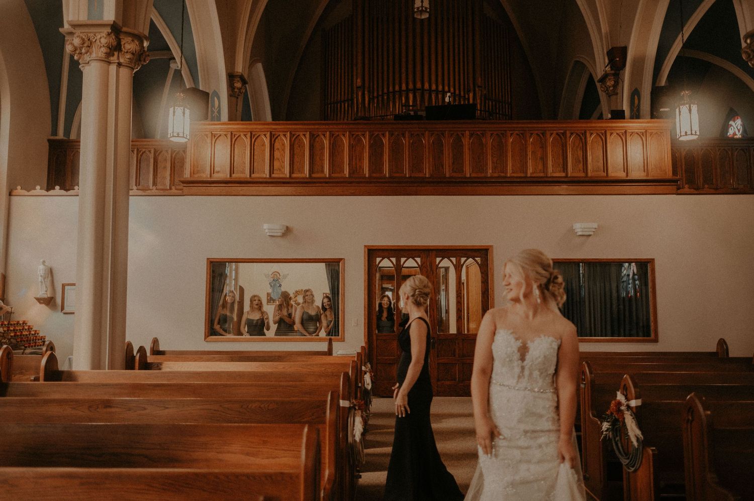 Wedding ceremony venue with wooden pews and arched architecture in warm lighting.