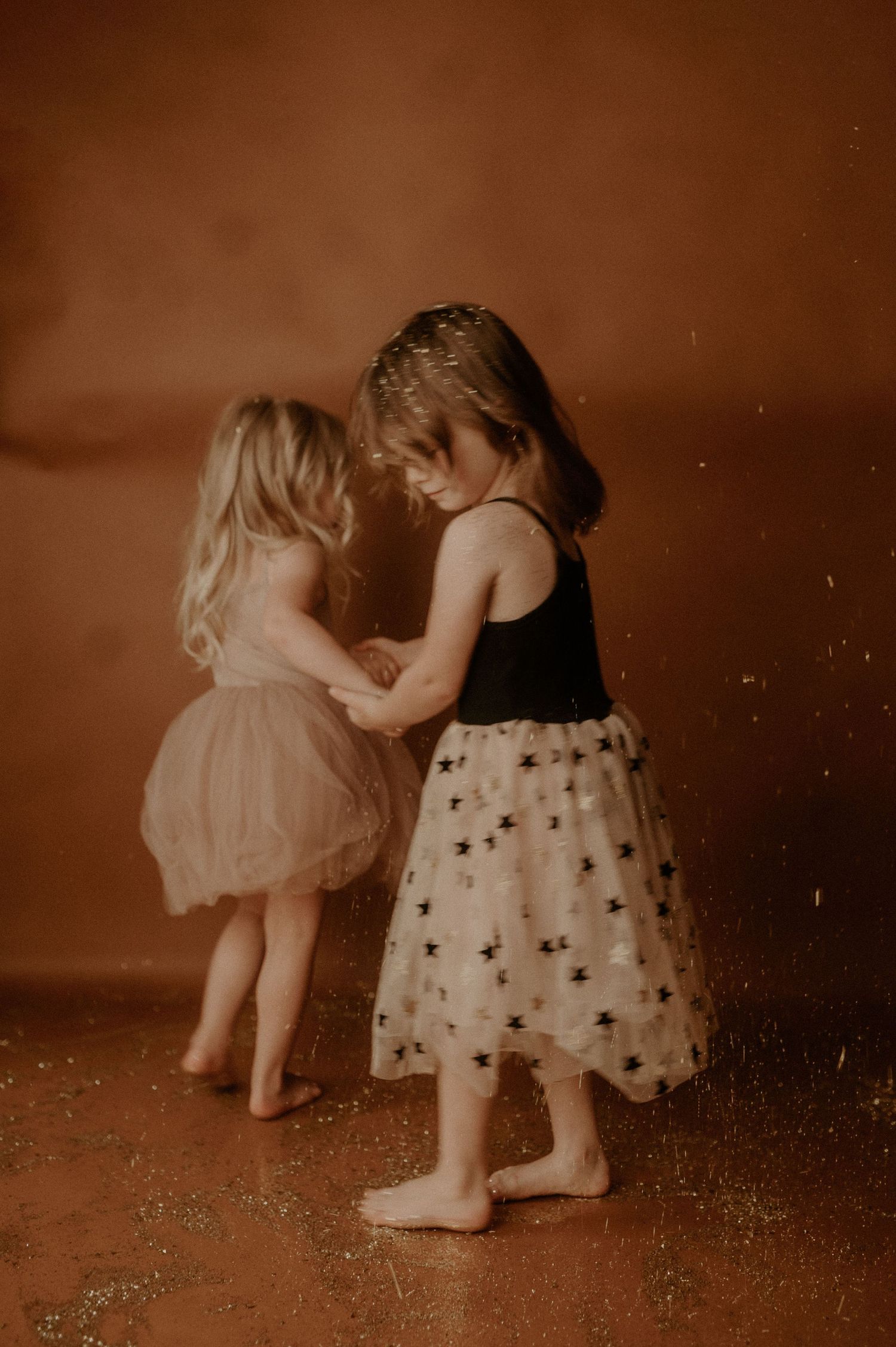 A sepia-toned series of photos showing small children in tulle dresses playing and dancing together.