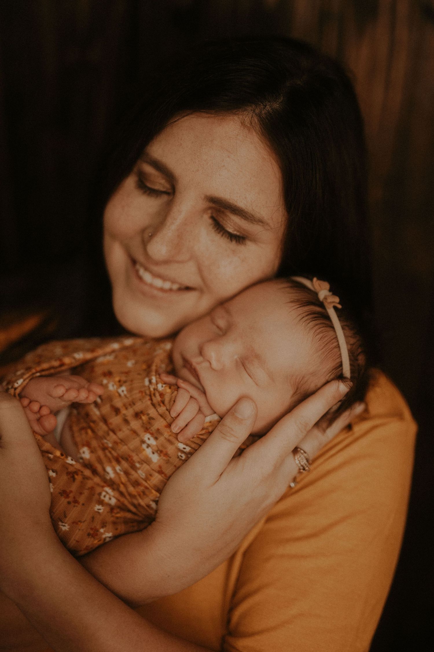A tender embrace between two people wearing orange and brown tones in a warmly lit intimate setting.