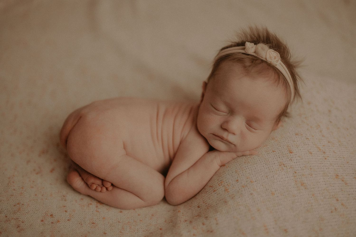 Serene newborn baby sleeping on textured background in natural light.
