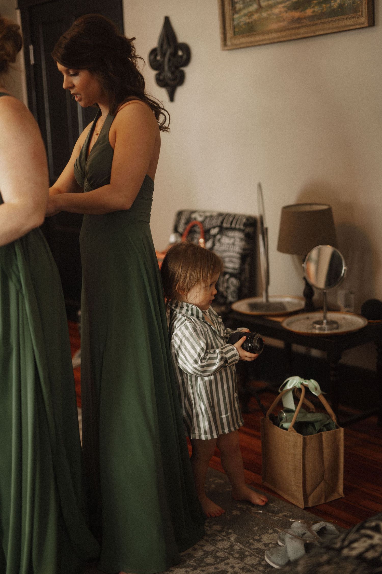 Women in elegant green dresses prepare for a wedding ceremony in an indoor setting.