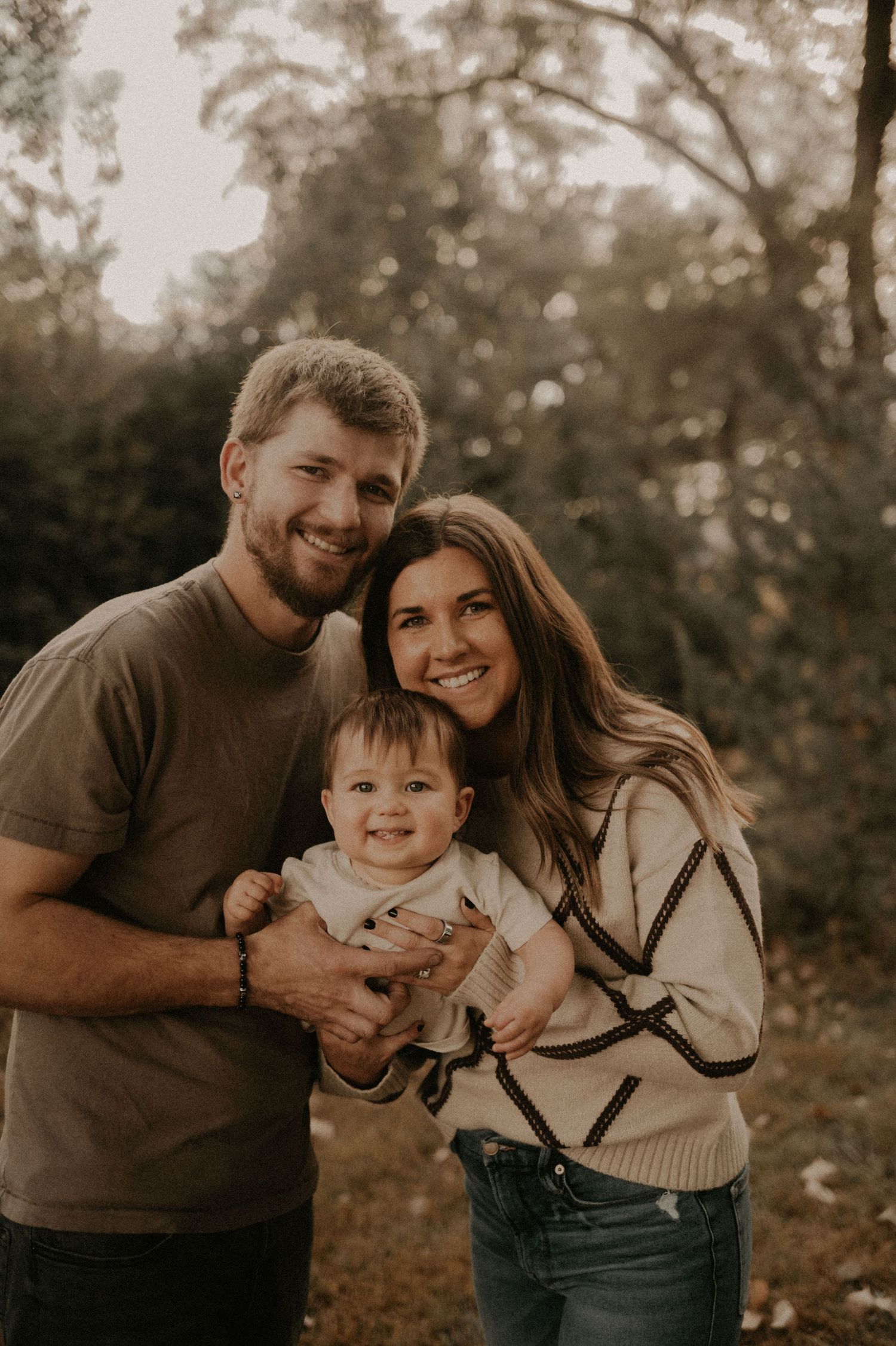 Family of three sharing joyful moments together in a natural outdoor setting.