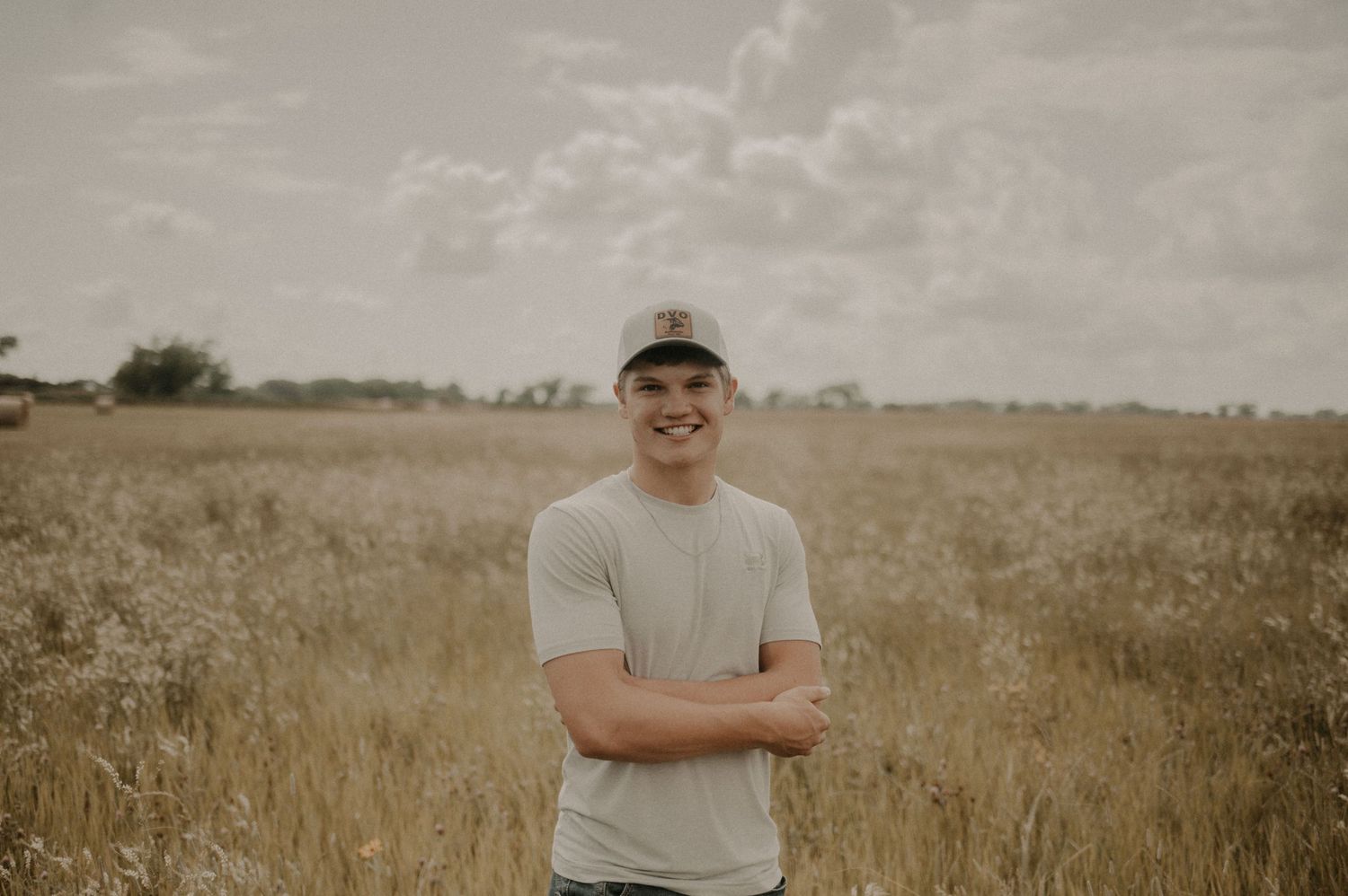 A series of six sepia-toned photographs showing someone posing in a rustic outdoor field setting at sunset.