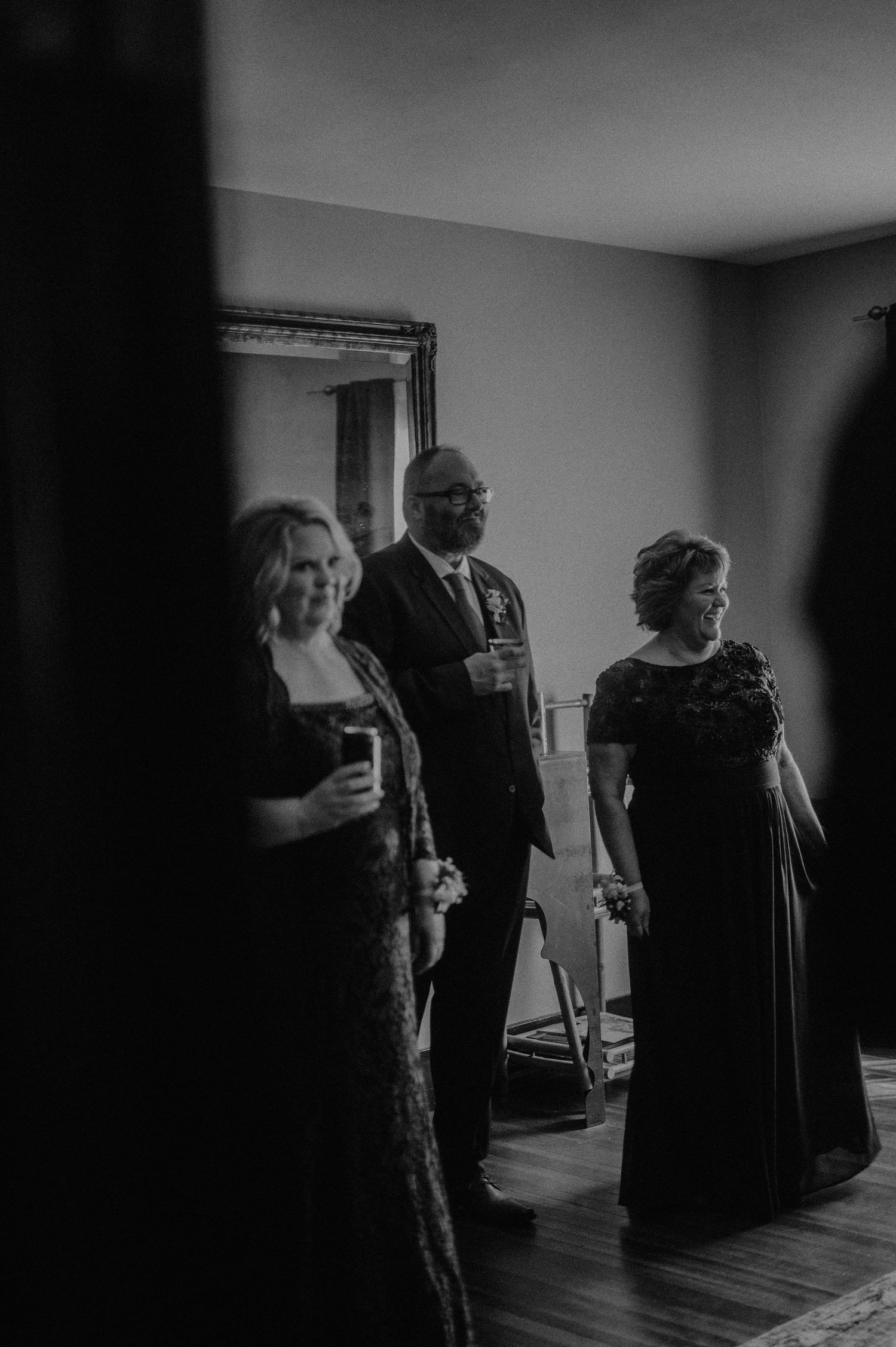 A black and white image of wedding guests in formal attire holding drinks.