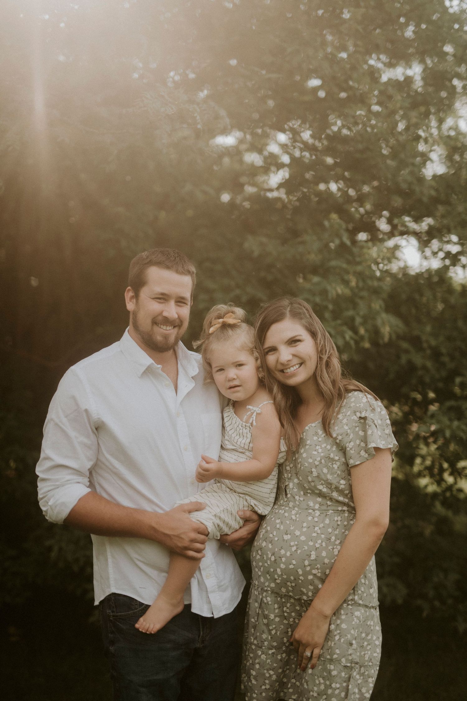 A family shares tender moments together during a golden hour photoshoot in a garden setting.