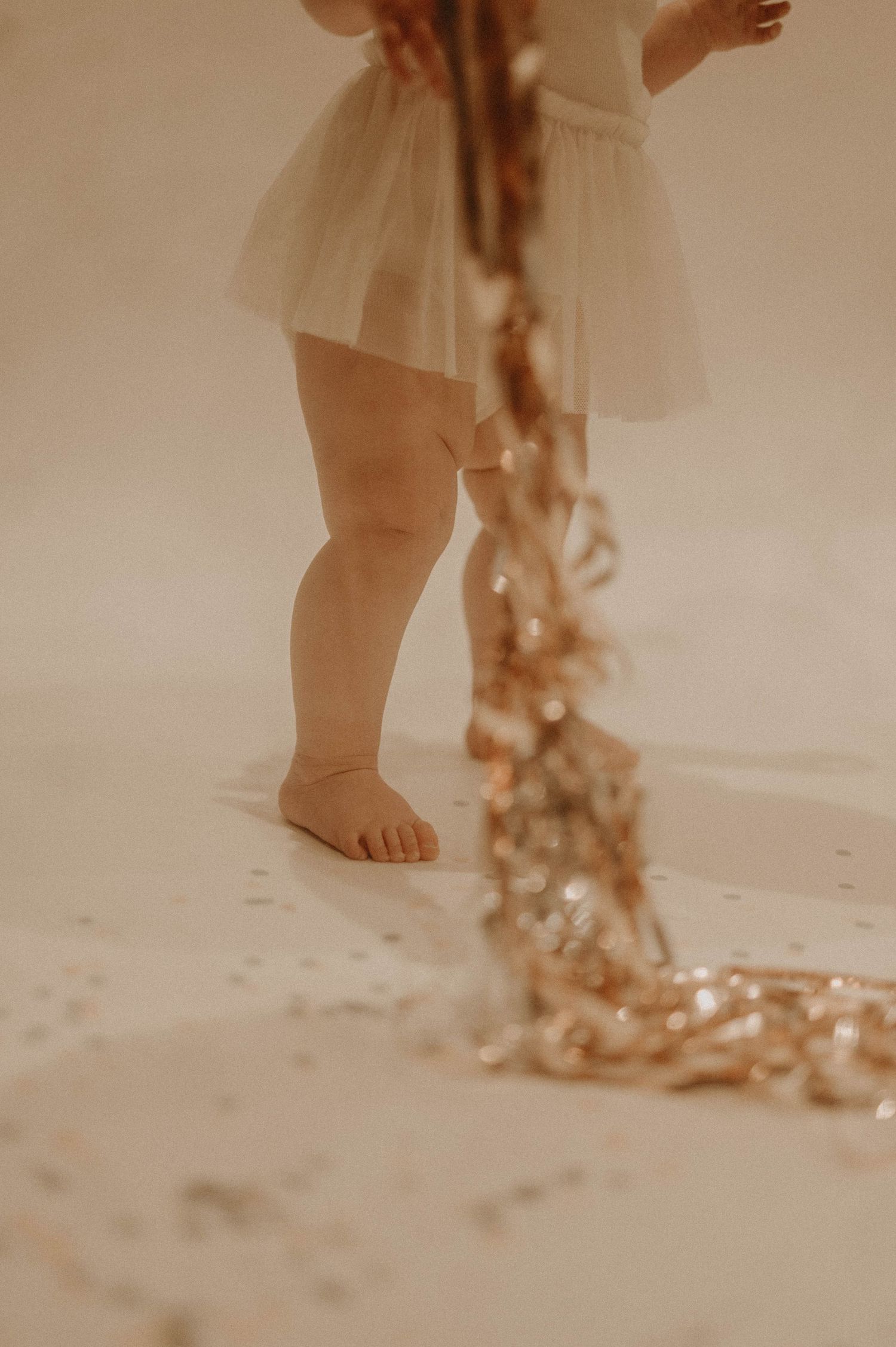 Close-up view of bare feet walking on sandy beach with dried flowers creating a dreamy, vintage atmosphere.