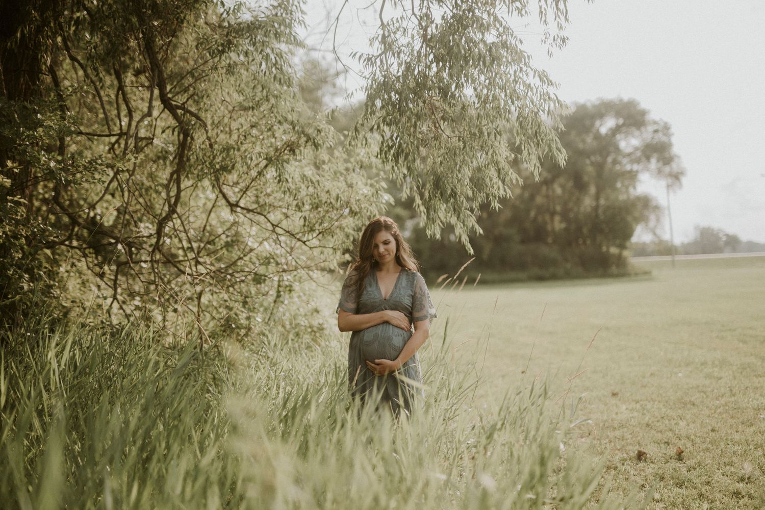 A series of romantic outdoor maternity photos taken in a sunlit meadow with trees in the background.