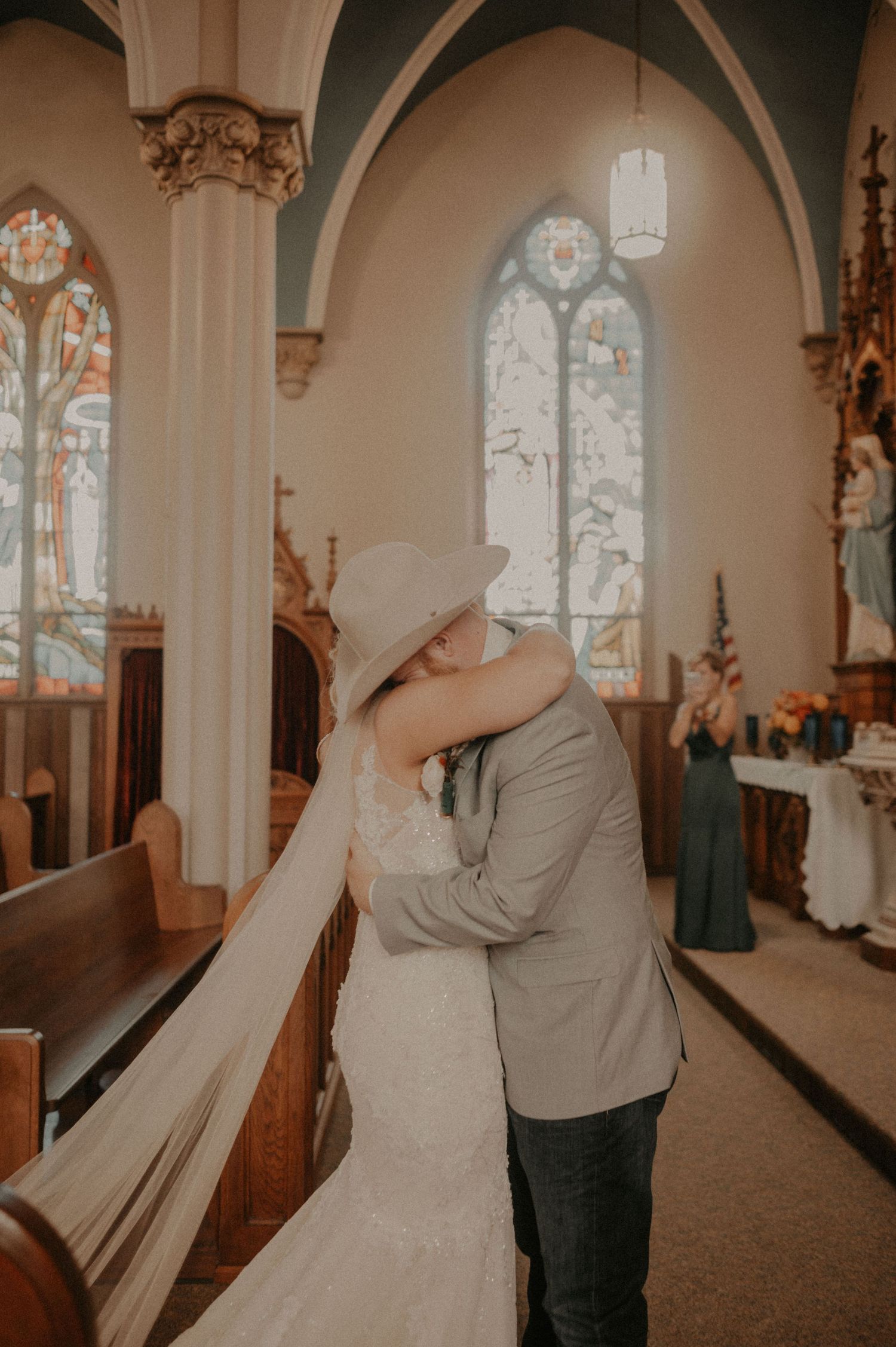 A romantic couple shares intimate moments in a church interior with arched windows and ornate architectural details.