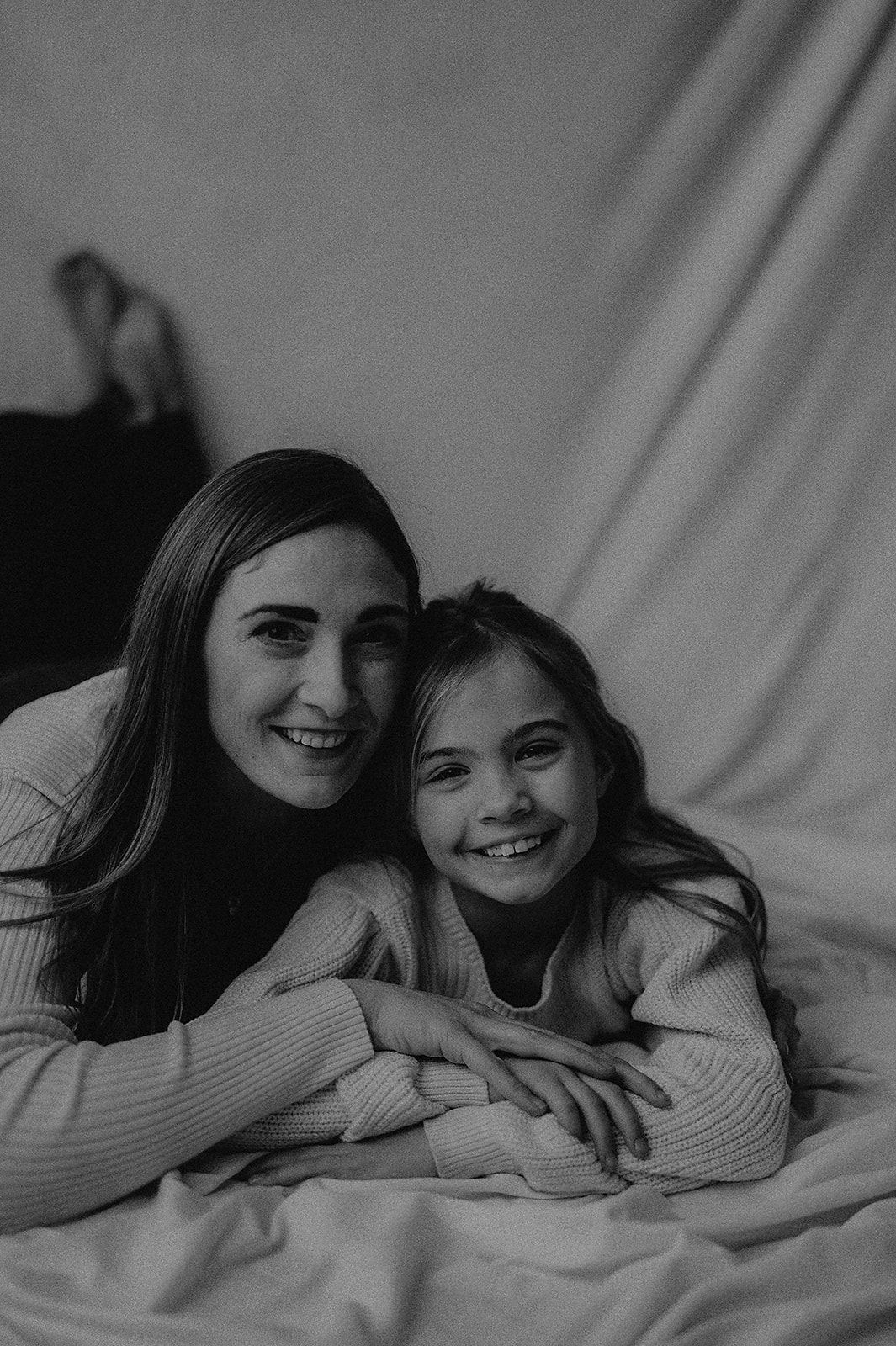 Black and white portrait series showing two people lying down and smiling together in casual intimate poses.