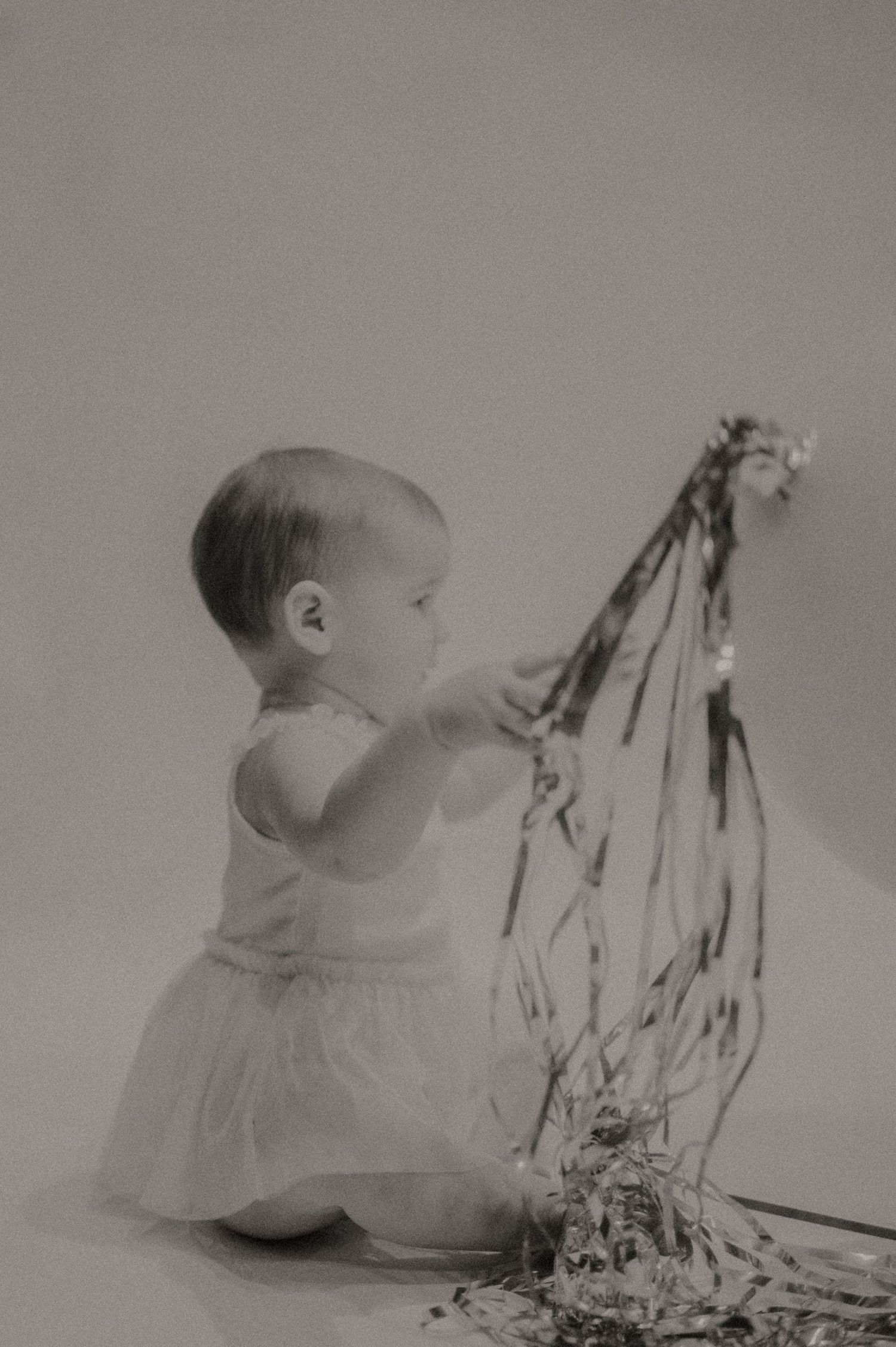 A series of vintage black and white photographs showing a baby playing with paper or fabric.