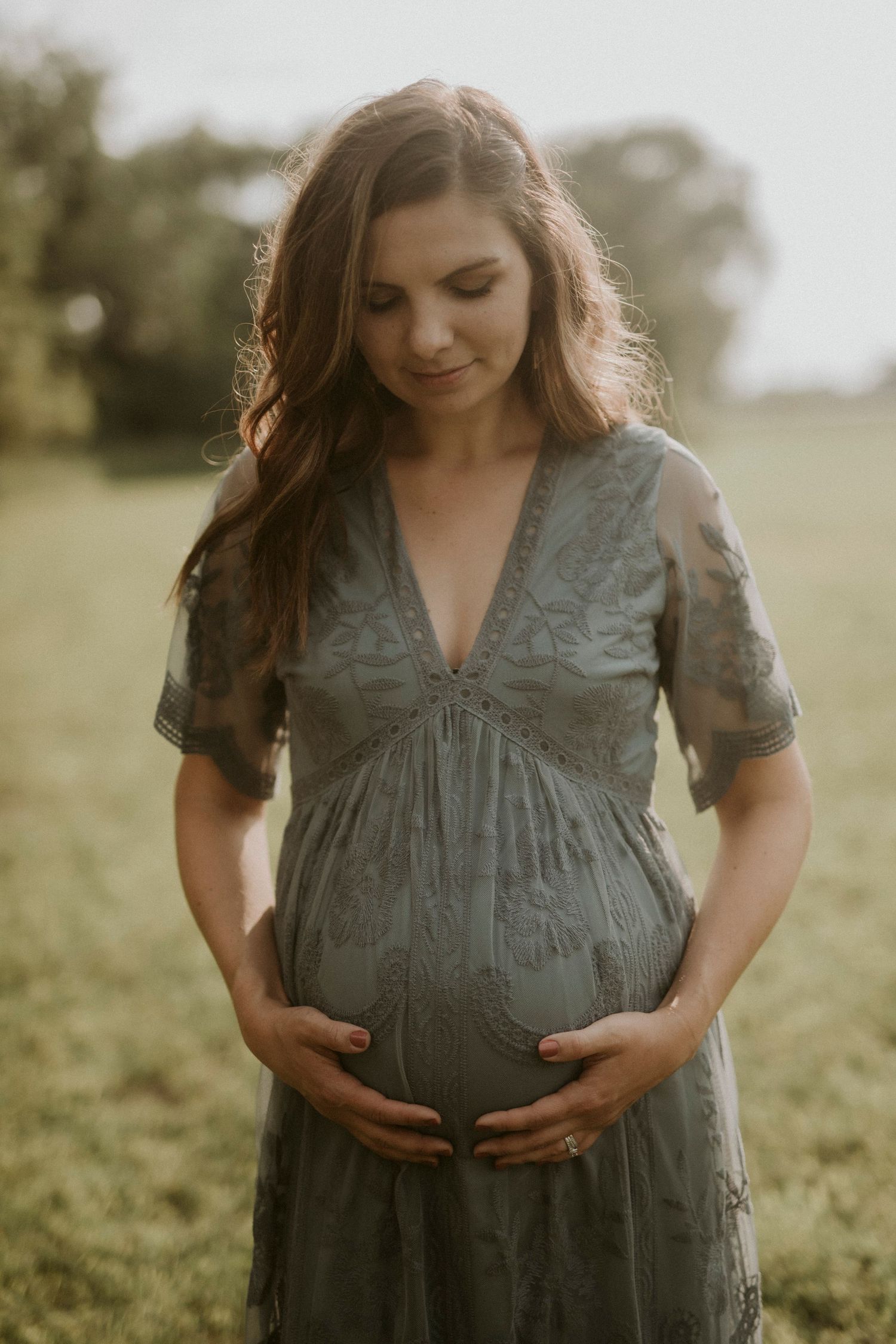 A maternity photo series shows someone in a green dress cradling their baby bump in a sunlit field.