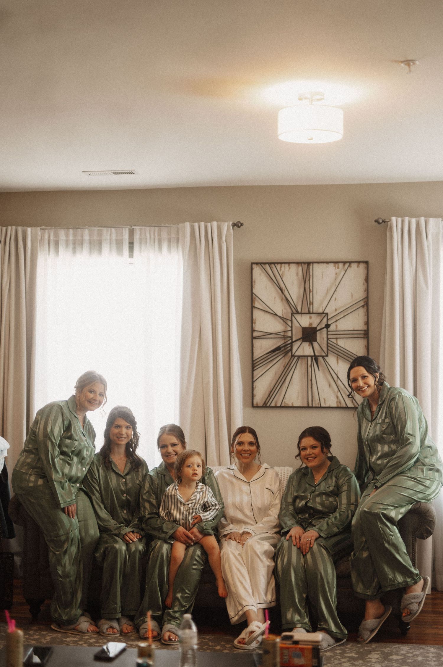 A group in matching green robes gather together laughing and enjoying a fun moment in a bright living room setting.