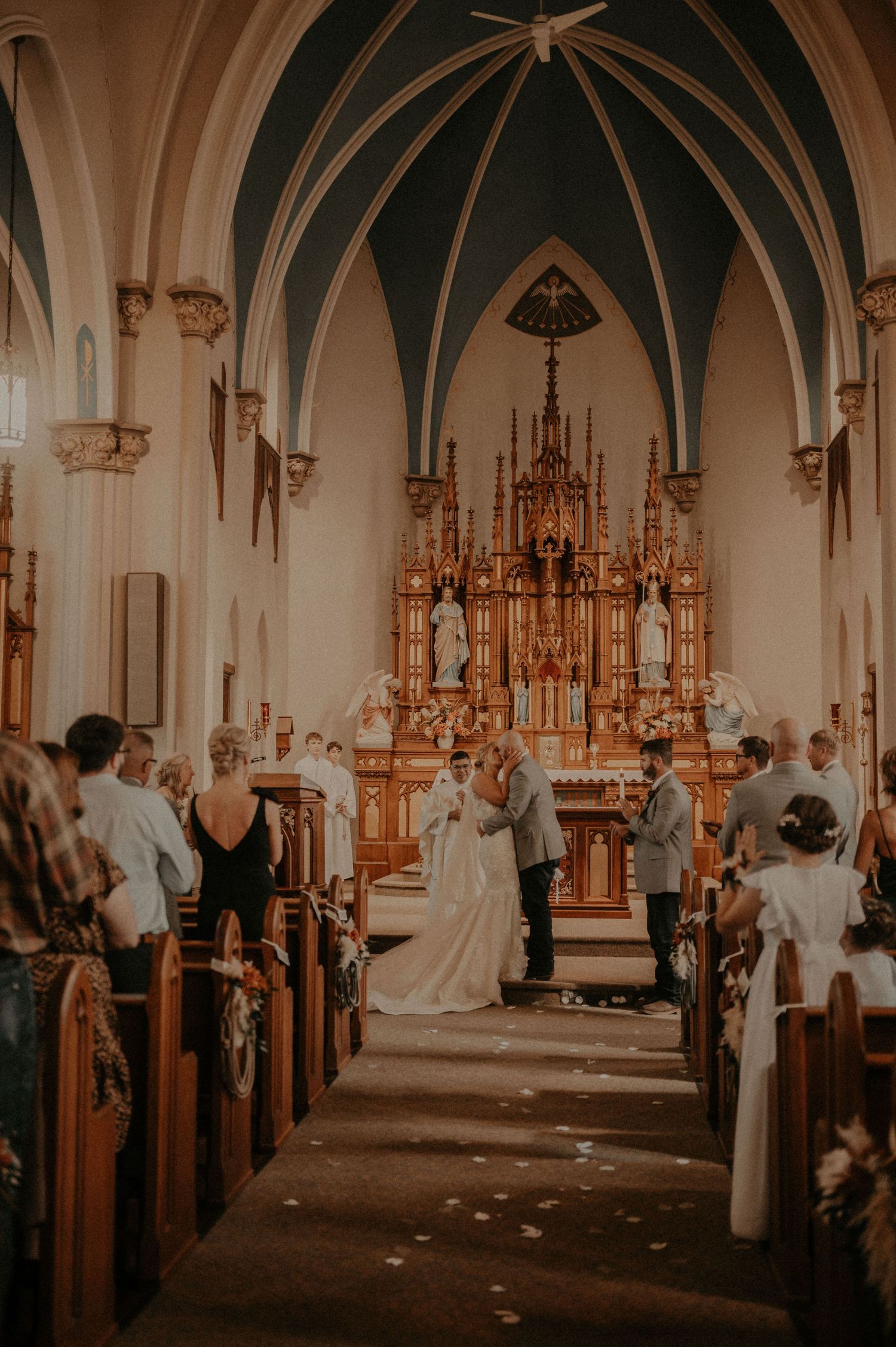 Wedding ceremony in a gothic-style church with vaulted ceilings and ornate altar decorations.