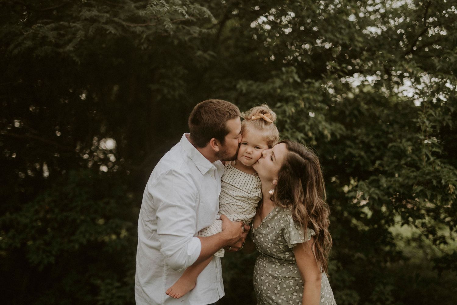 A family shares a tender moment together outdoors in a natural setting during golden hour.