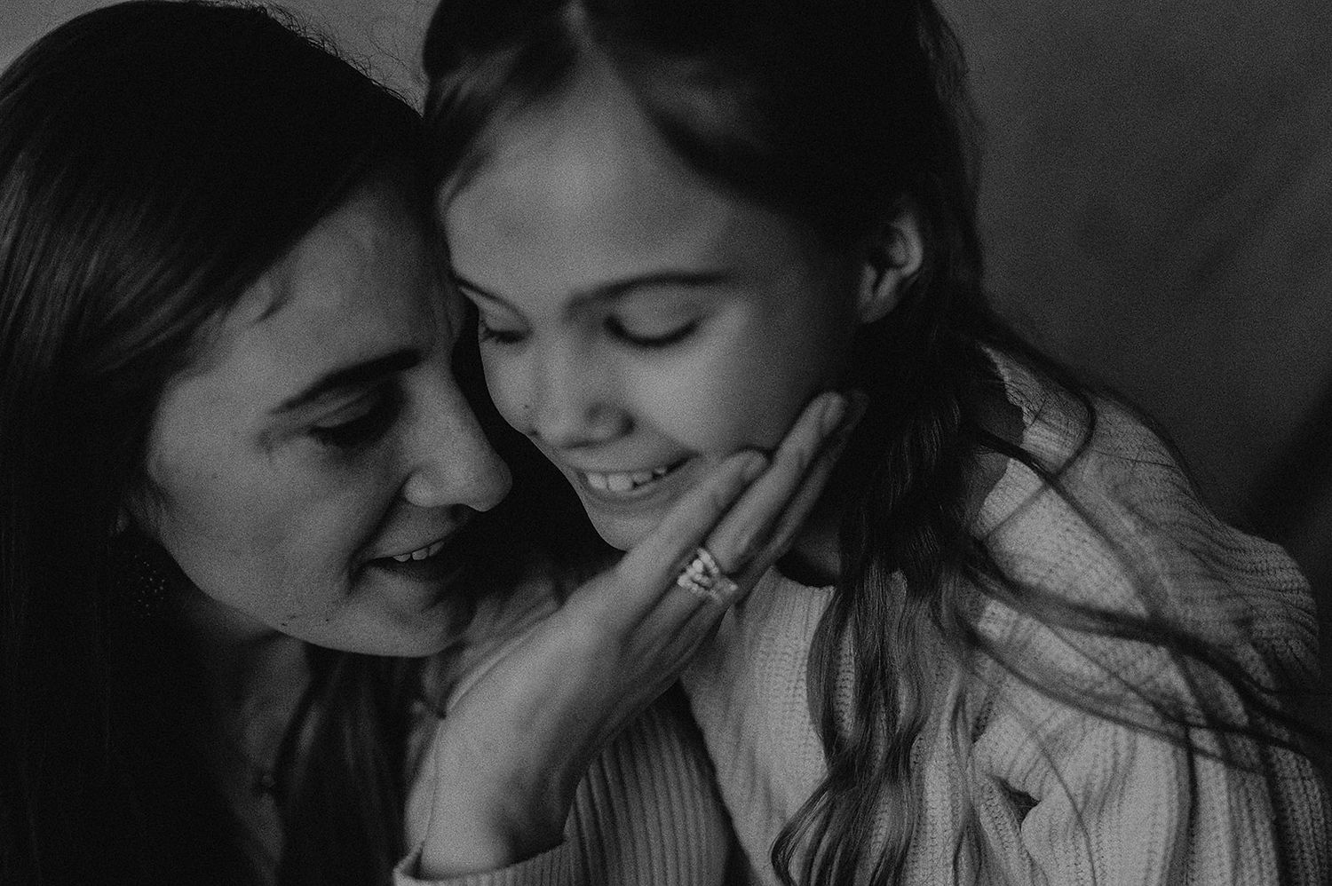 Intimate black and white photograph capturing tender moment between two people in close embrace.