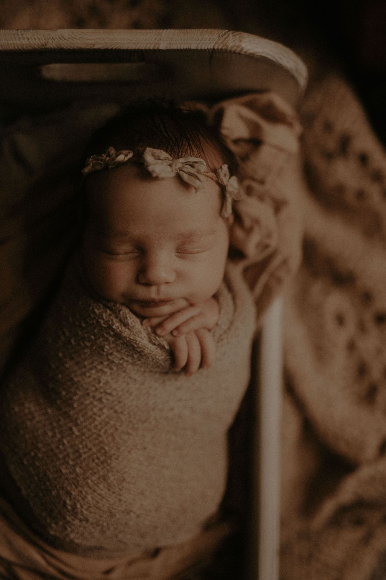 A sepia-toned collection of newborn baby photos showing a sleeping infant wrapped in soft knit blankets.
