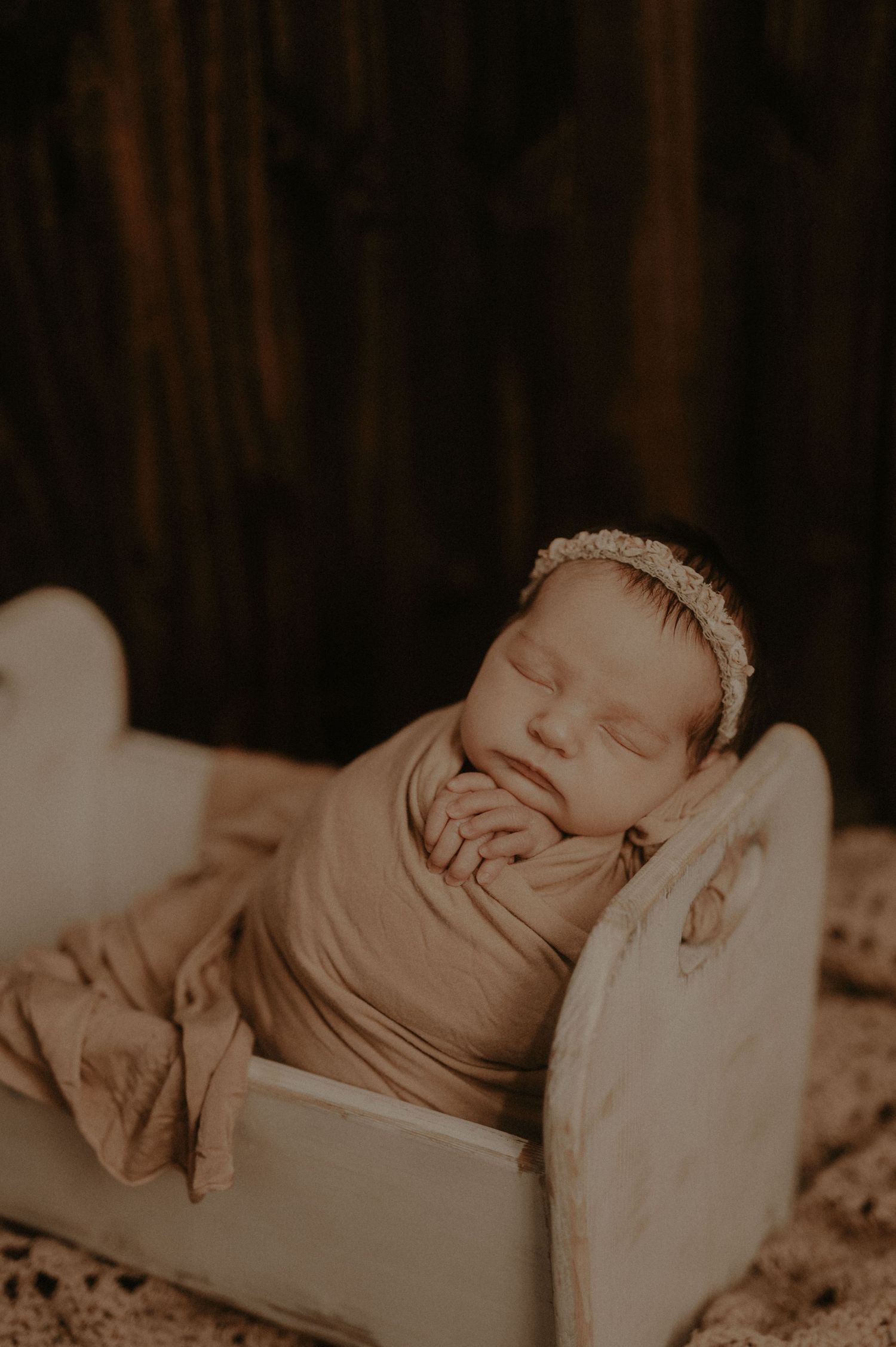 A sepia-toned photo collage shows a sleeping newborn baby in various peaceful poses on soft blankets.