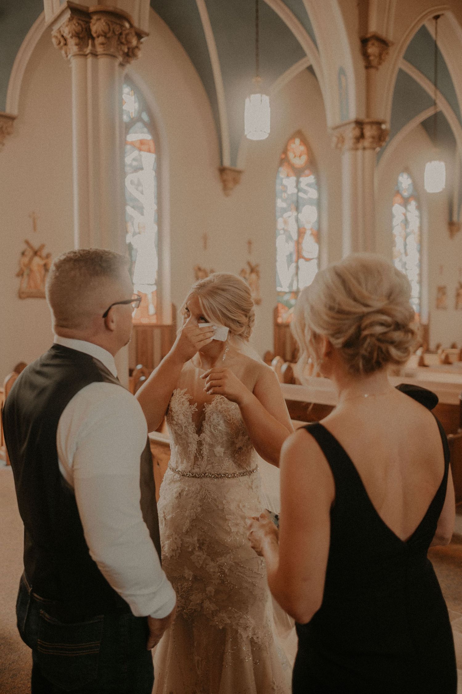 A candid moment inside a church with elegant Gothic arches and stained glass windows in warm lighting.