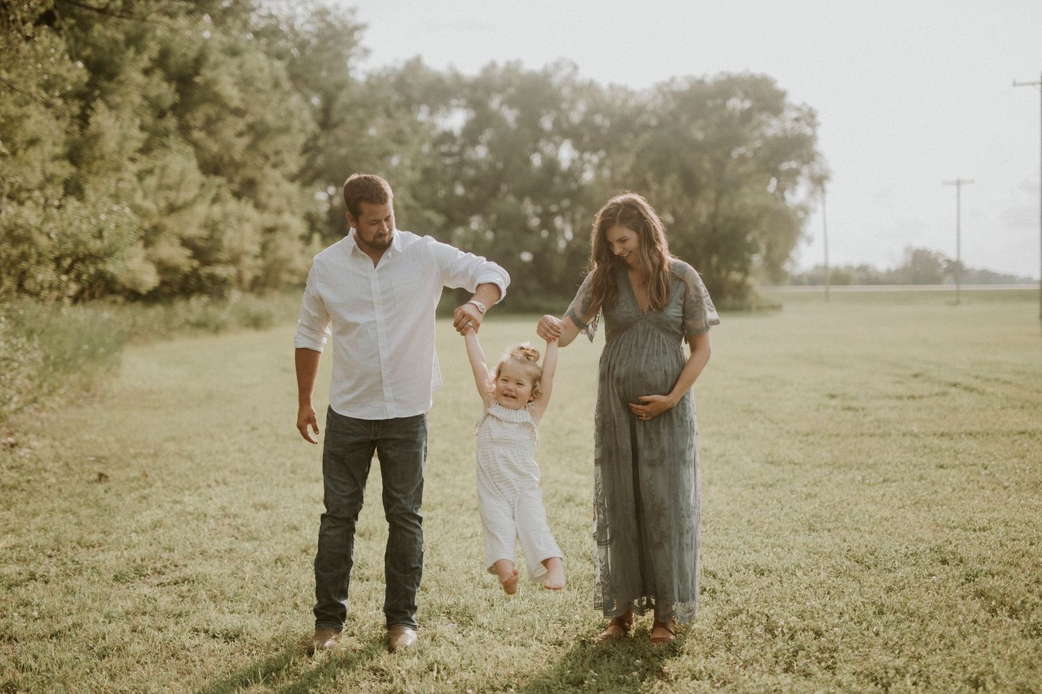 A family walks together through a sun-drenched meadow during golden hour creating a warm and joyful outdoor scene.