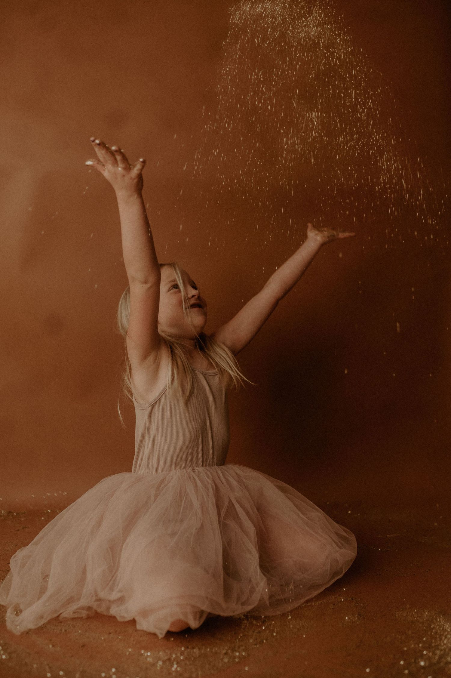 A series of artistic sepia-toned photos showing a dancer in a flowing dress performing graceful movements on the floor.