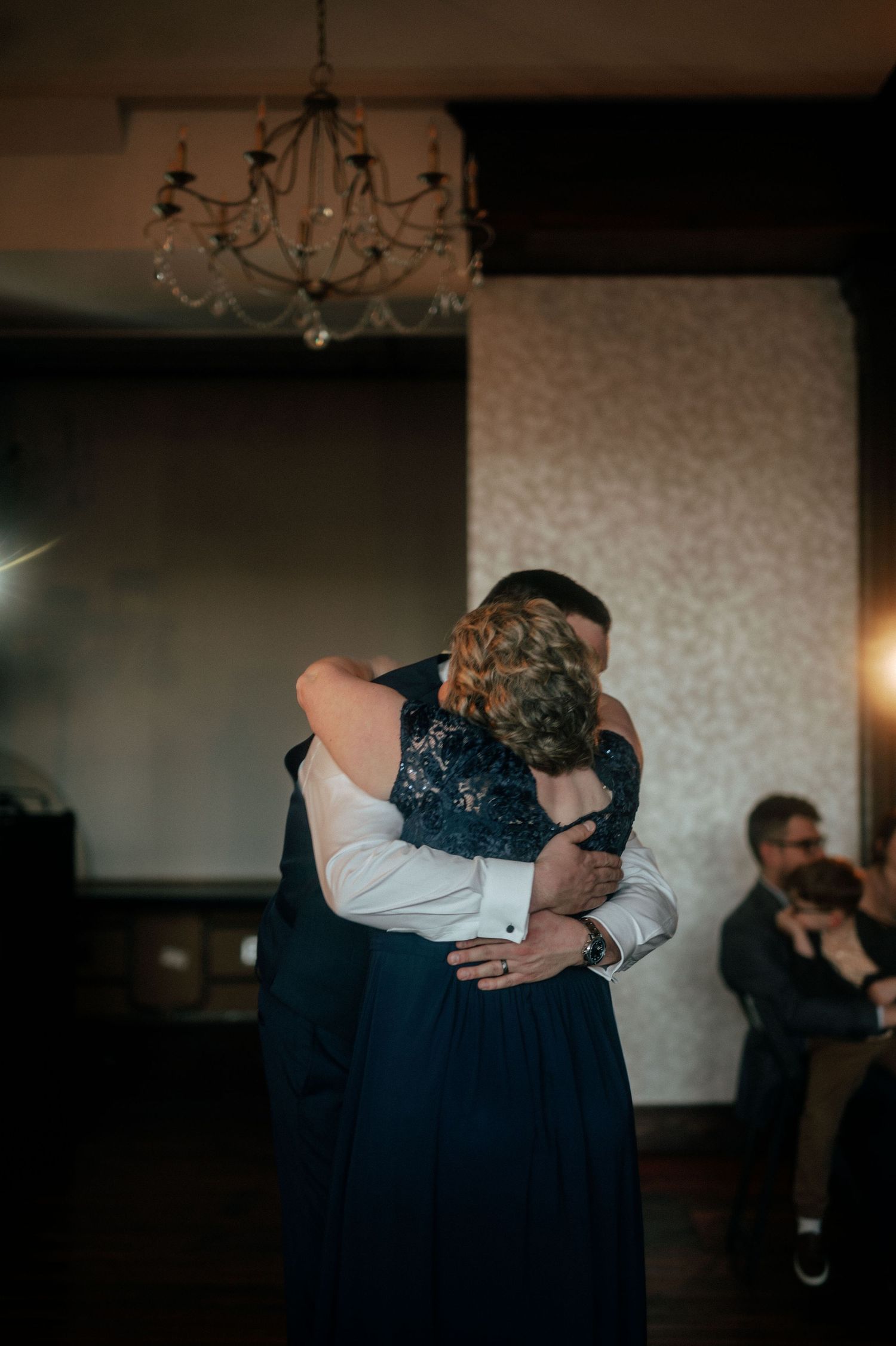 Couple shares emotional embrace during wedding dance in elegant venue.