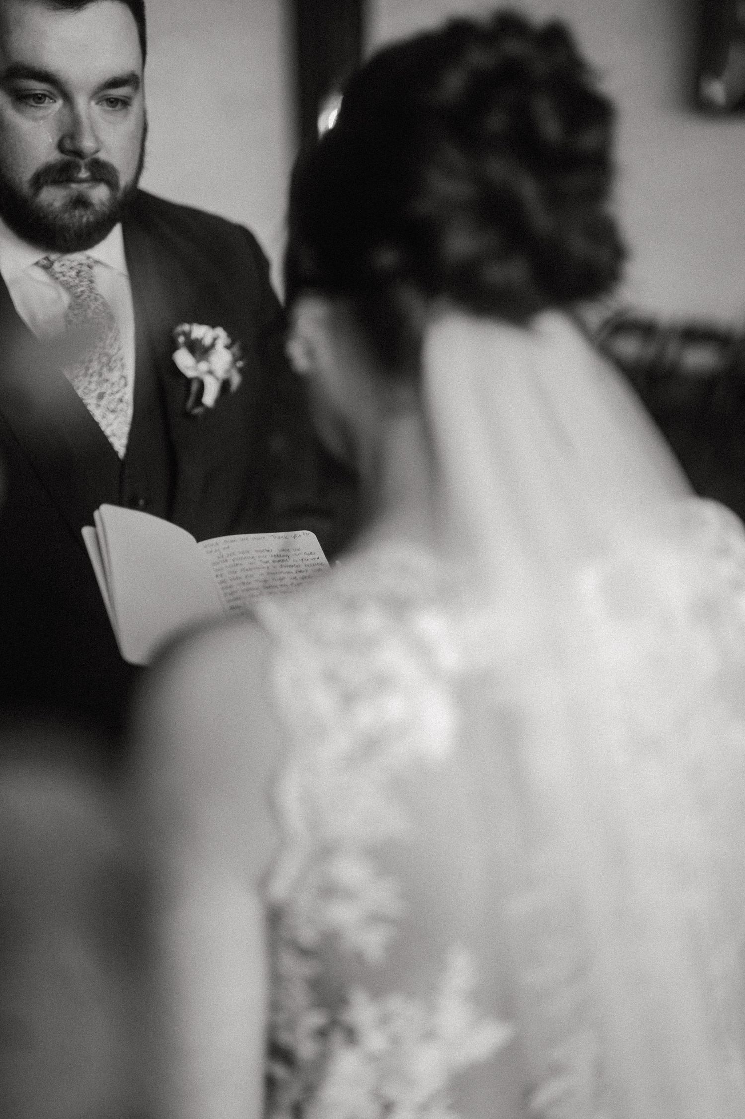 A black and white intimate moment during wedding vow reading.