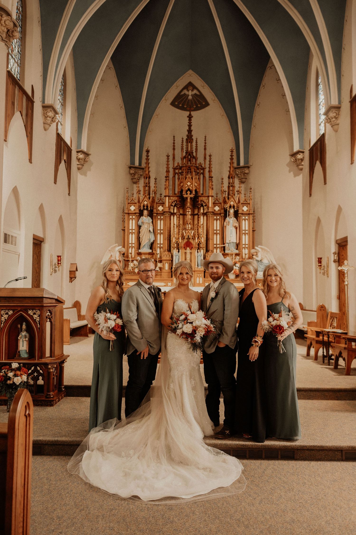 Wedding party poses in front of a grand cathedral altar with gothic architecture.