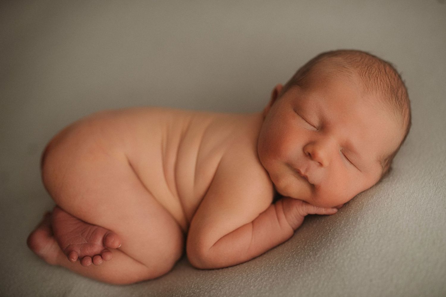 Serene newborn portrait with minimalist styling and gentle lighting.