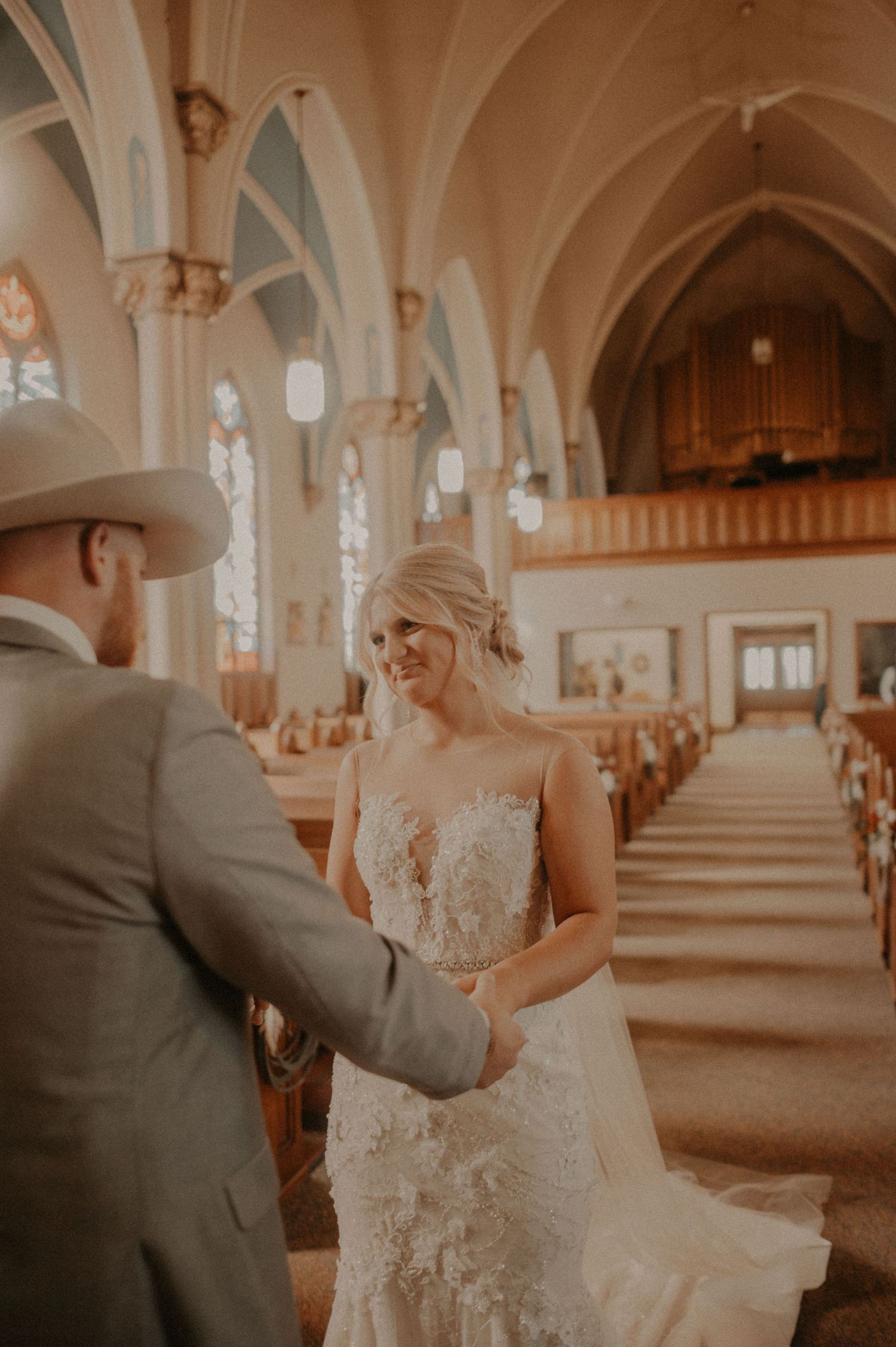 Romantic wedding scene in a cathedral with ornate architectural details and stained glass windows.