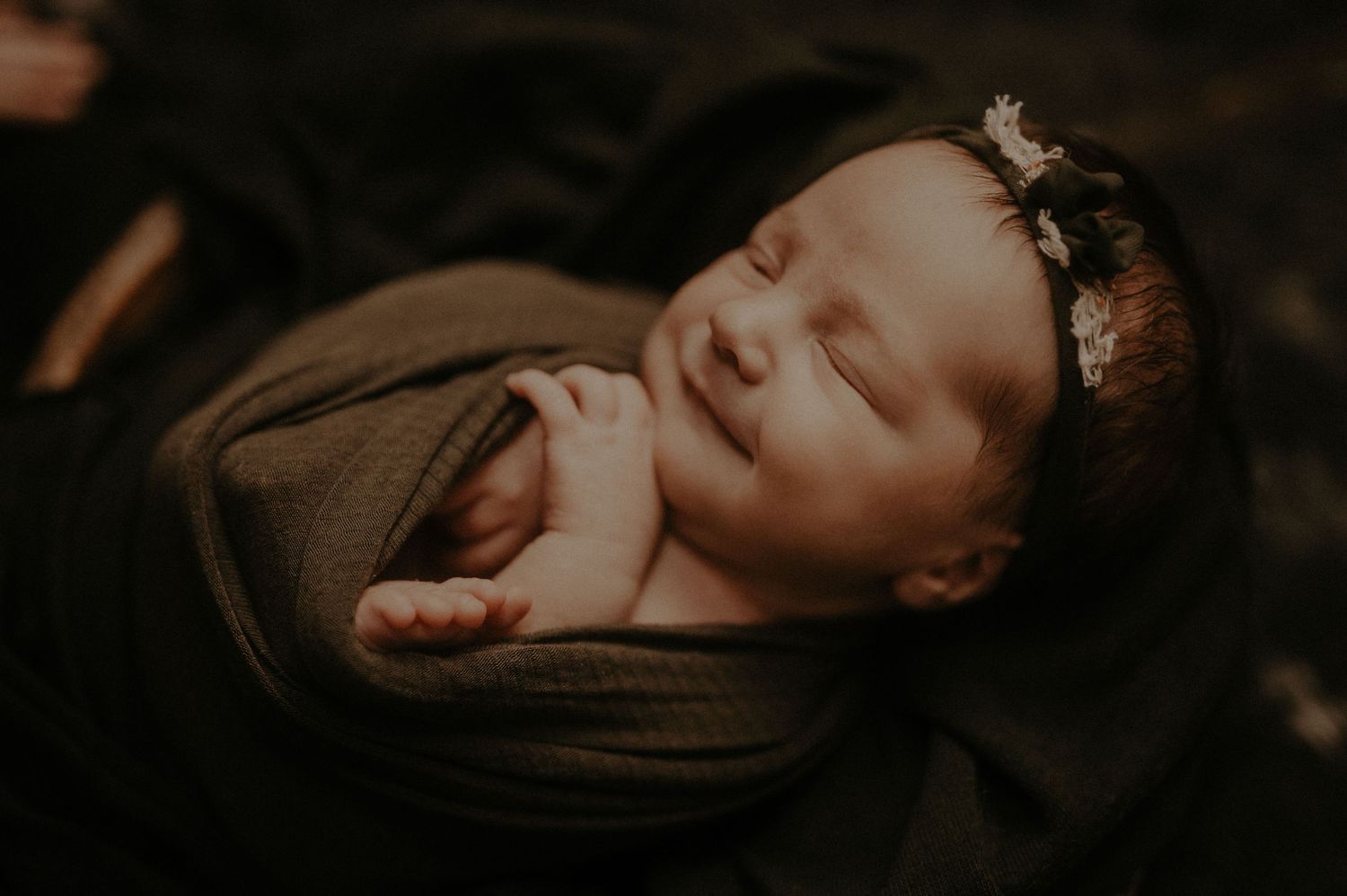 Artistic moody portrait in warm sepia tones showing a figure in repose against a dark background.
