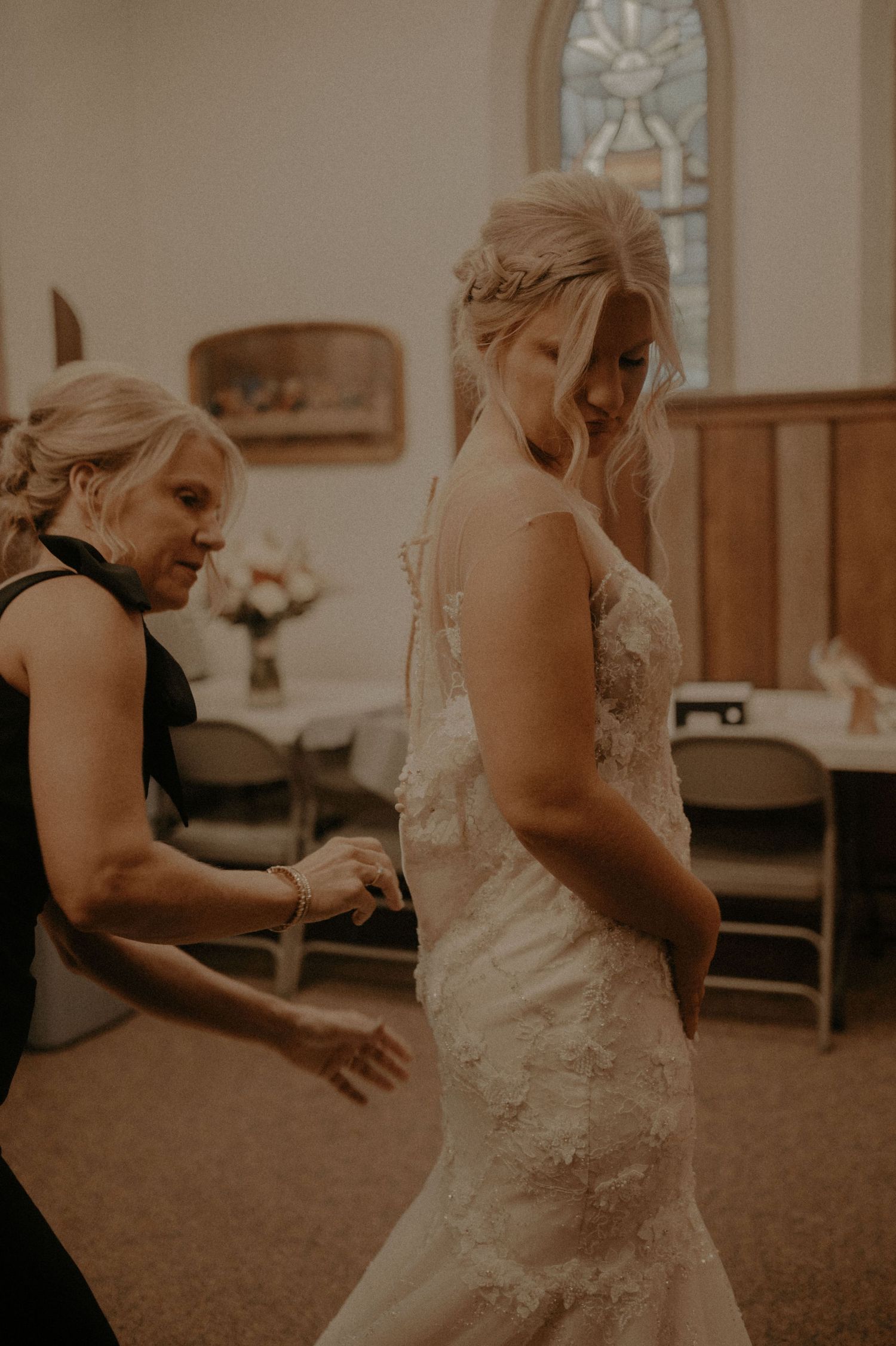 A wedding dress fitting session in a church room with natural lighting.