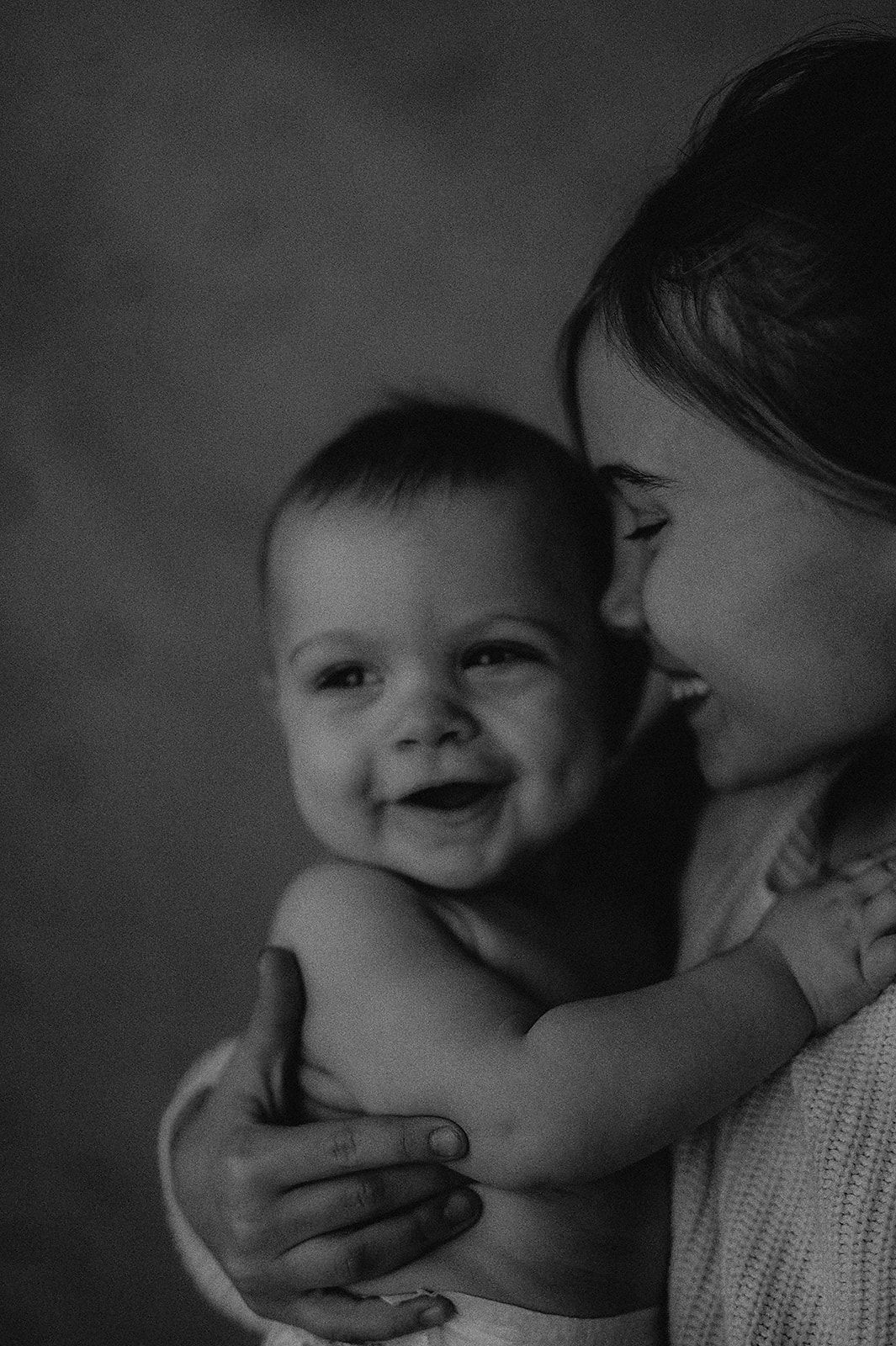 Intimate black and white photos capturing tender moments between parent and infant.